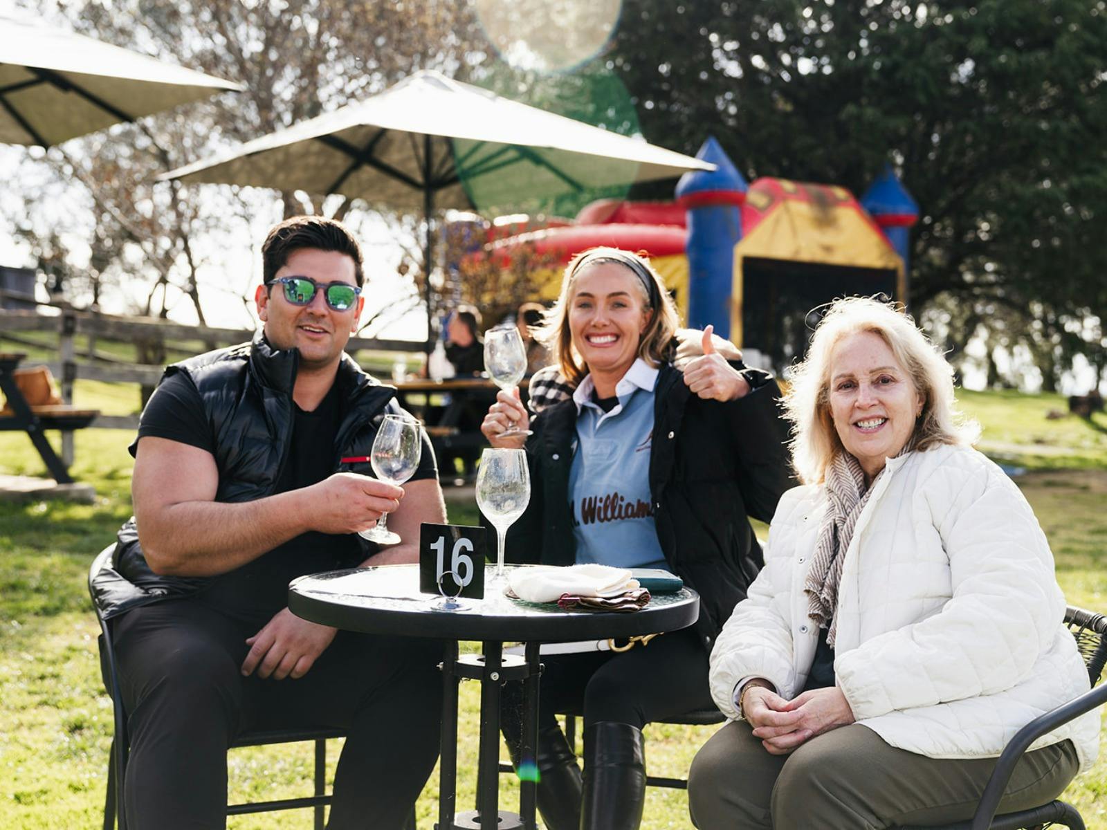 A man and two women at Stockman's Ridge wines smiling and giving the camera a thumbs up with wine