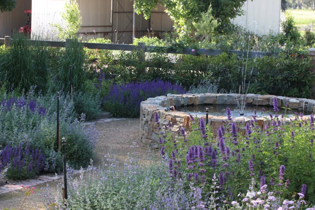 Picture of a garden pond and pathway with flower beds surrounding it.