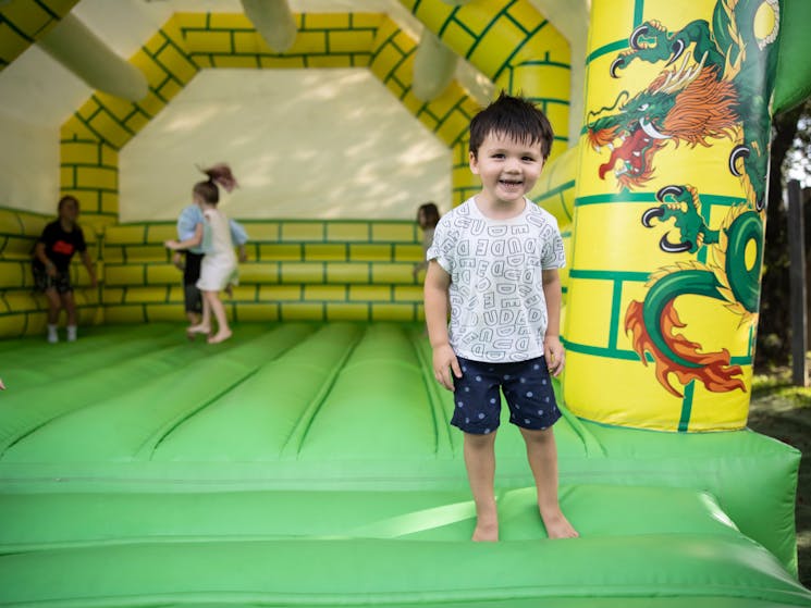 Green and yellow bouncy castle with a young boy smiling at the camera