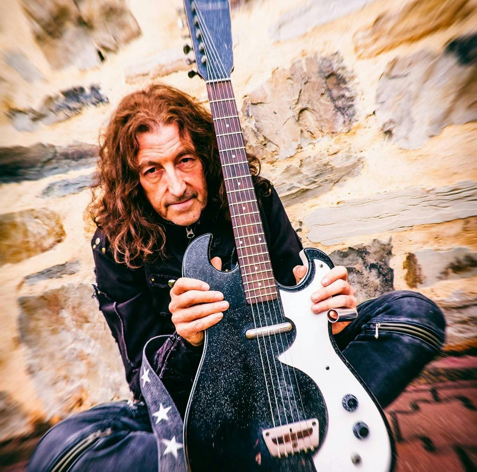 A man crouching with a guitar