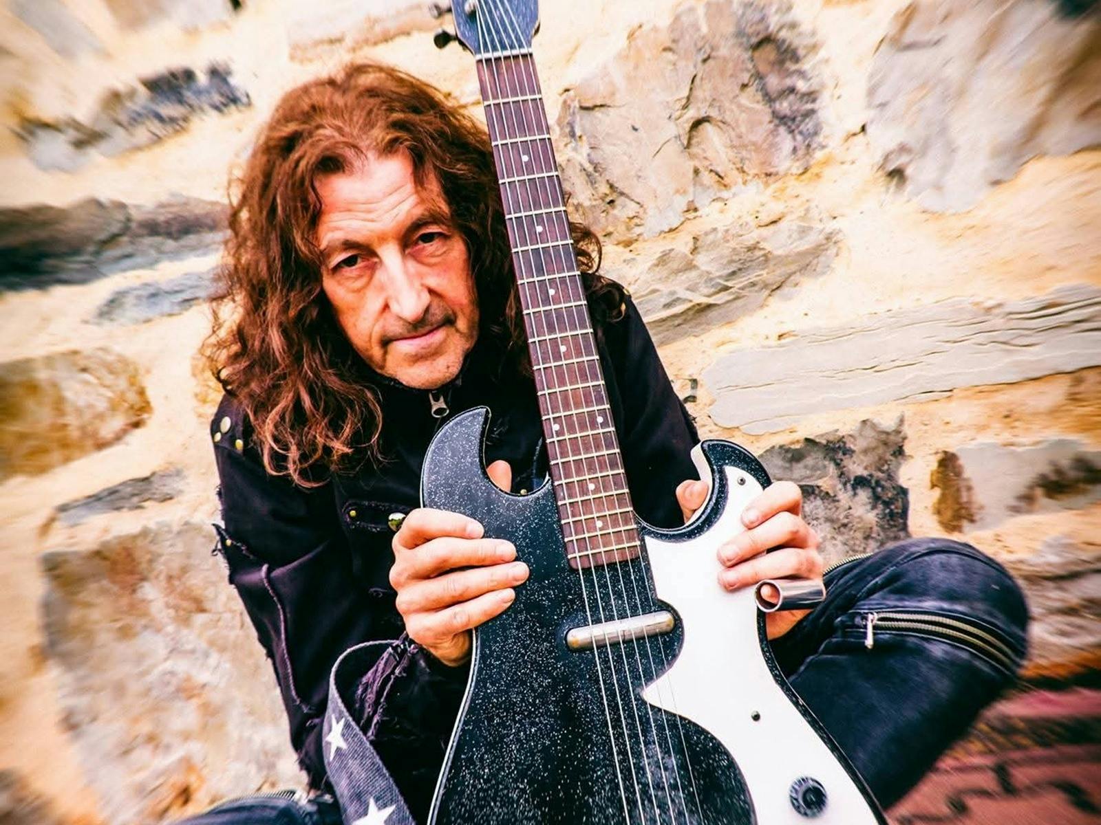 A man crouching with a guitar