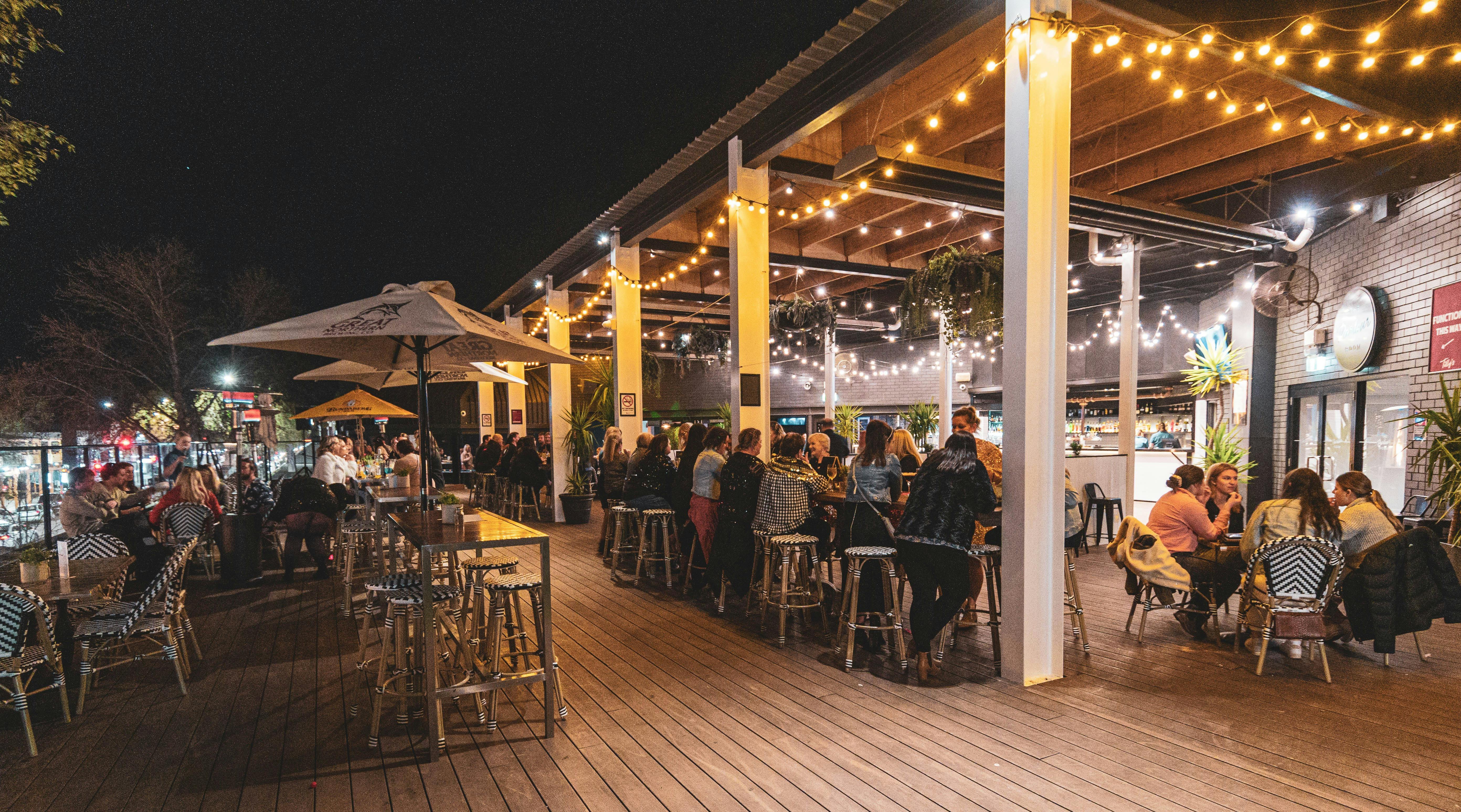 A night time photo of the Tilly's Deck area with people enjoying company of their friends at a table