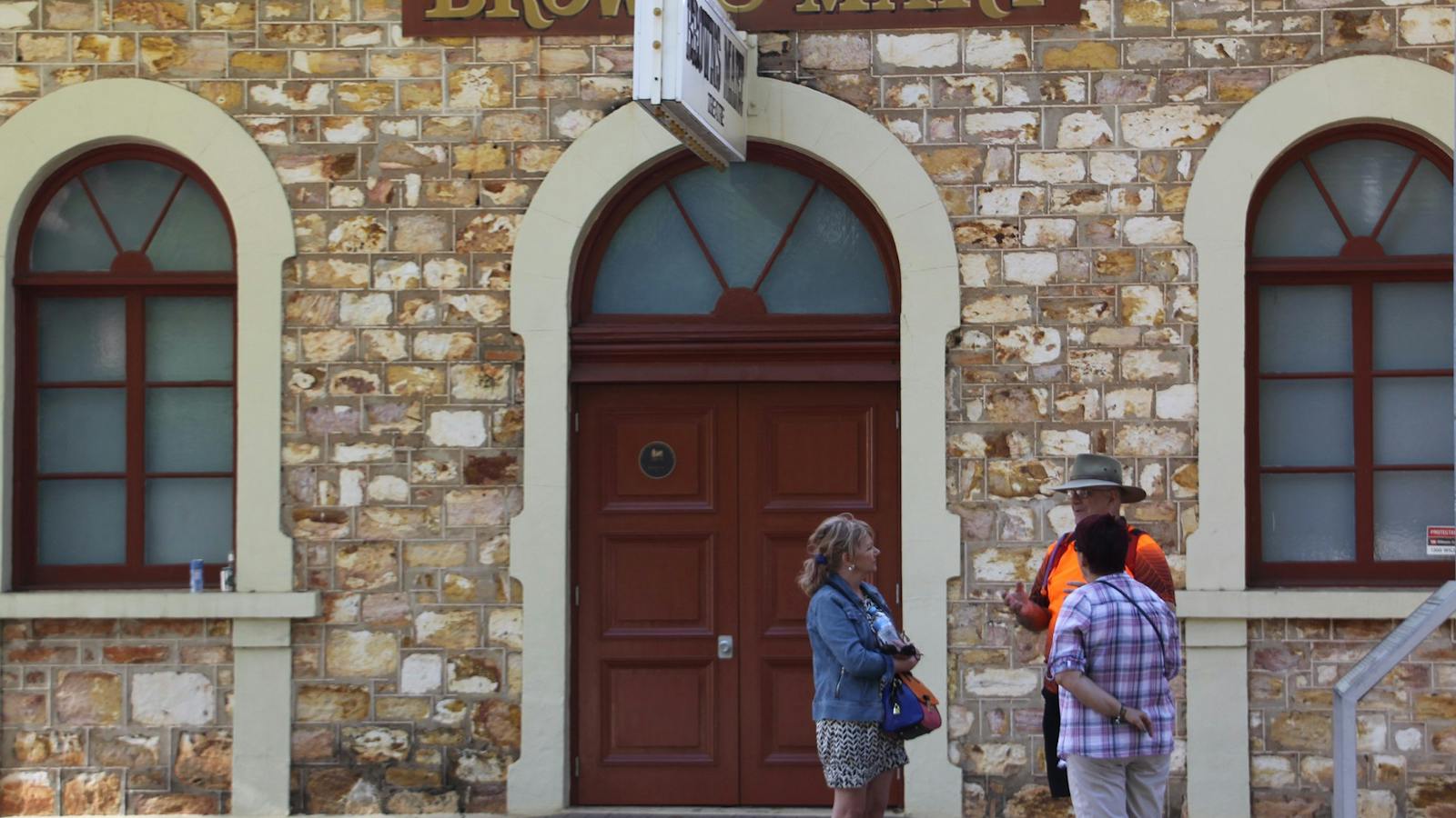 Guide and guests standing talking outside historic Browns Mart building