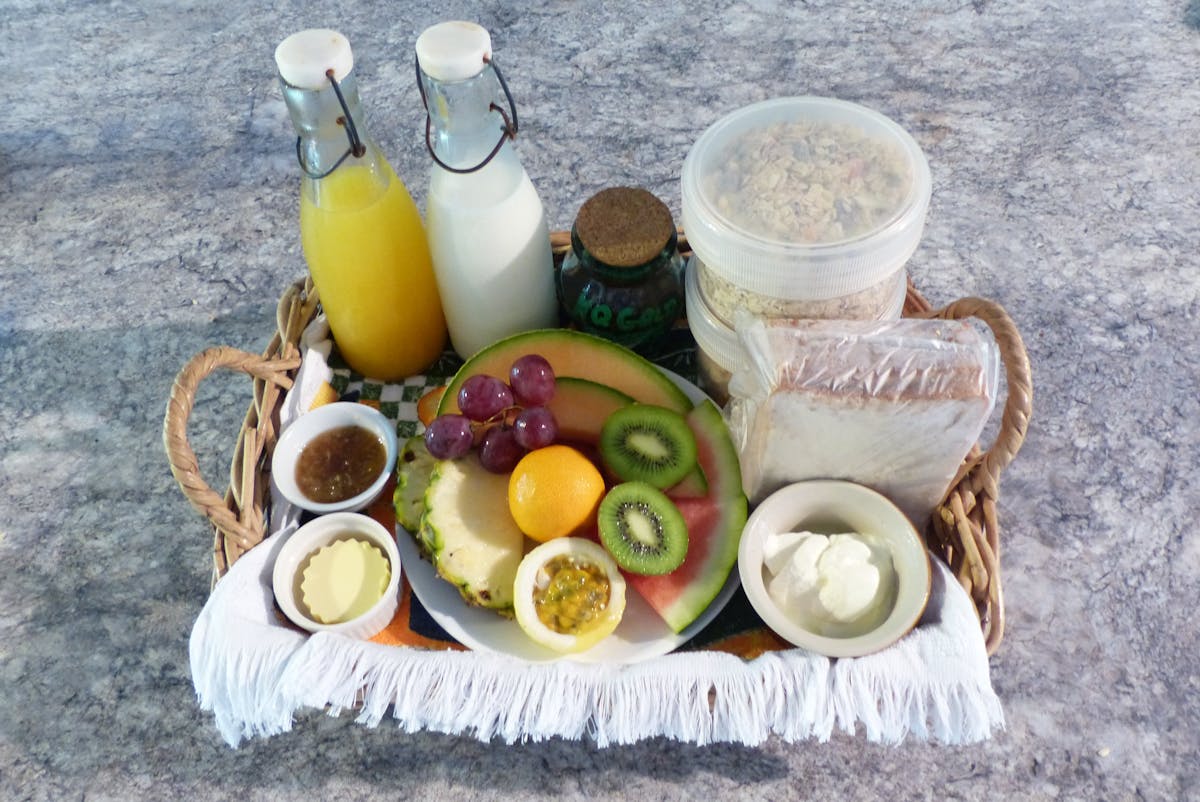Basket containing fruits, cereals, jam, yoghurt, milk, juice and bread