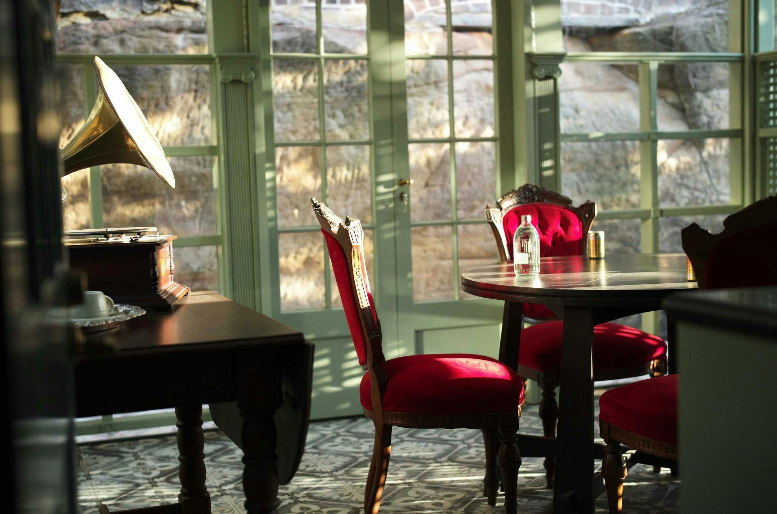 陽光明媚的溫室配有紅色天鵝絨餐椅、復古唱片機和華麗的裝飾。