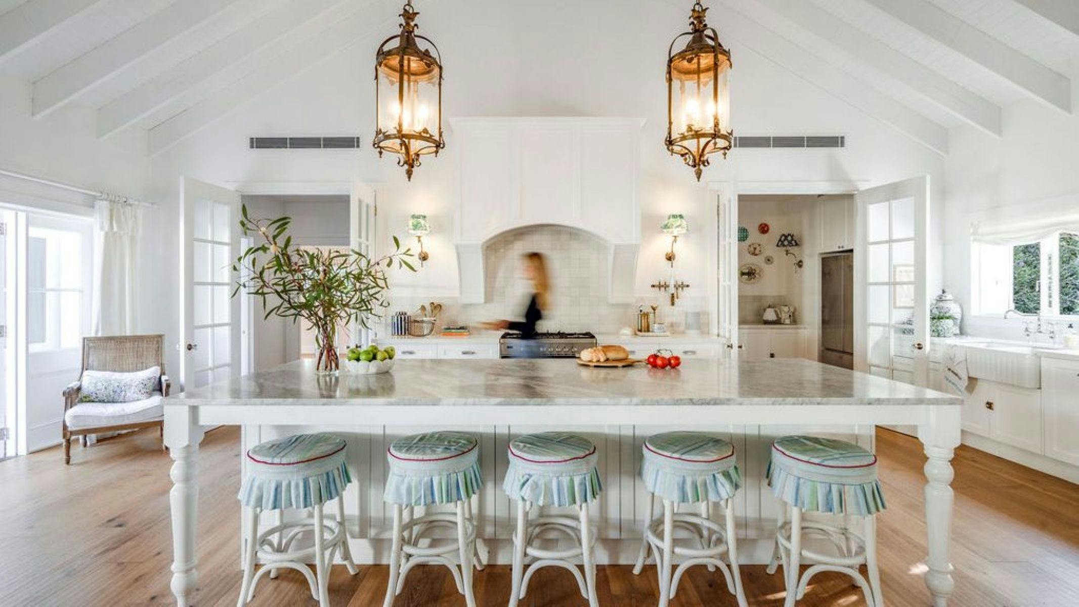 Image of lady walking through the kitchen past the enormous kitchen island bench