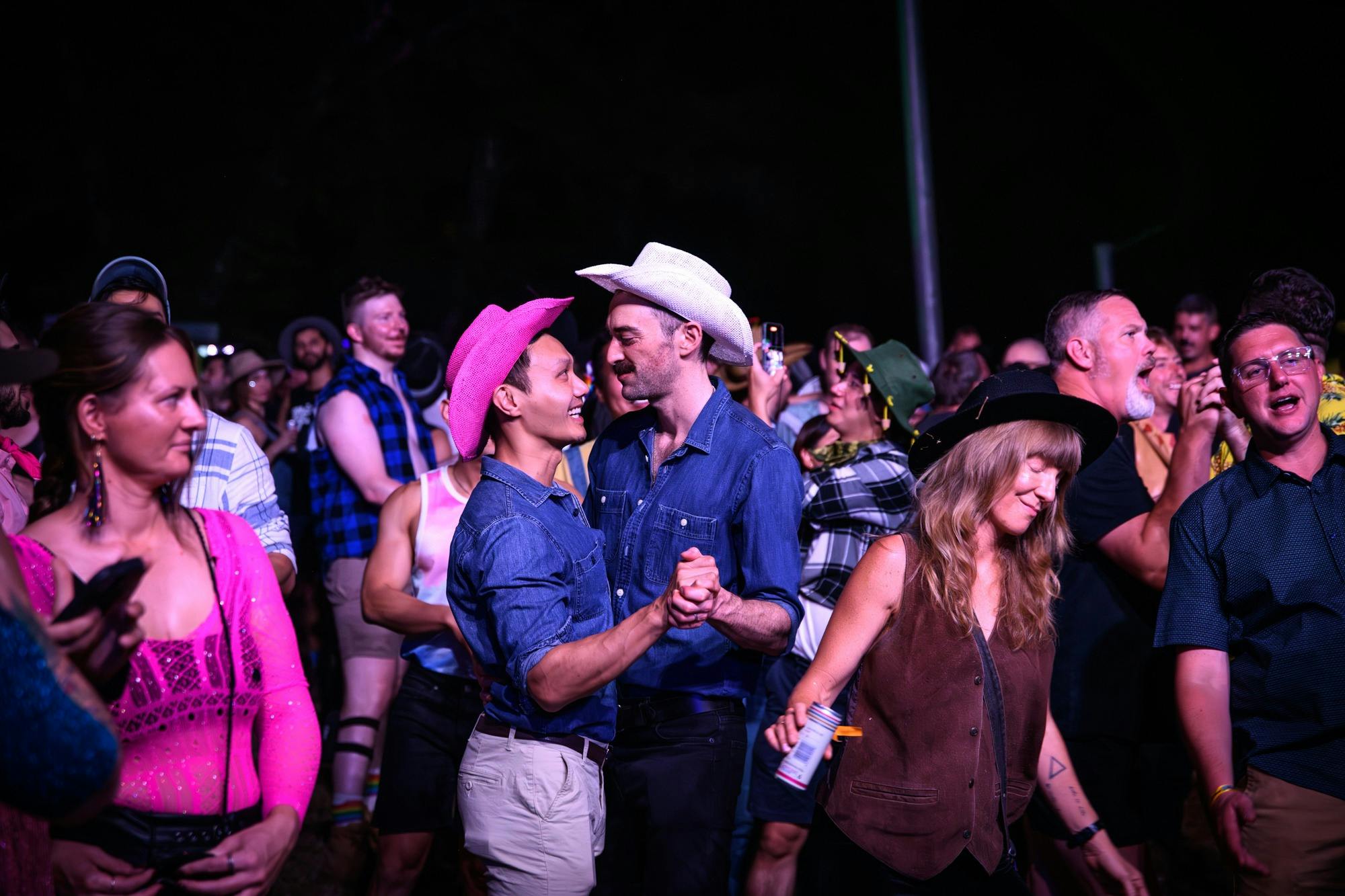 couple wearing cowboy hats dancing in crowd