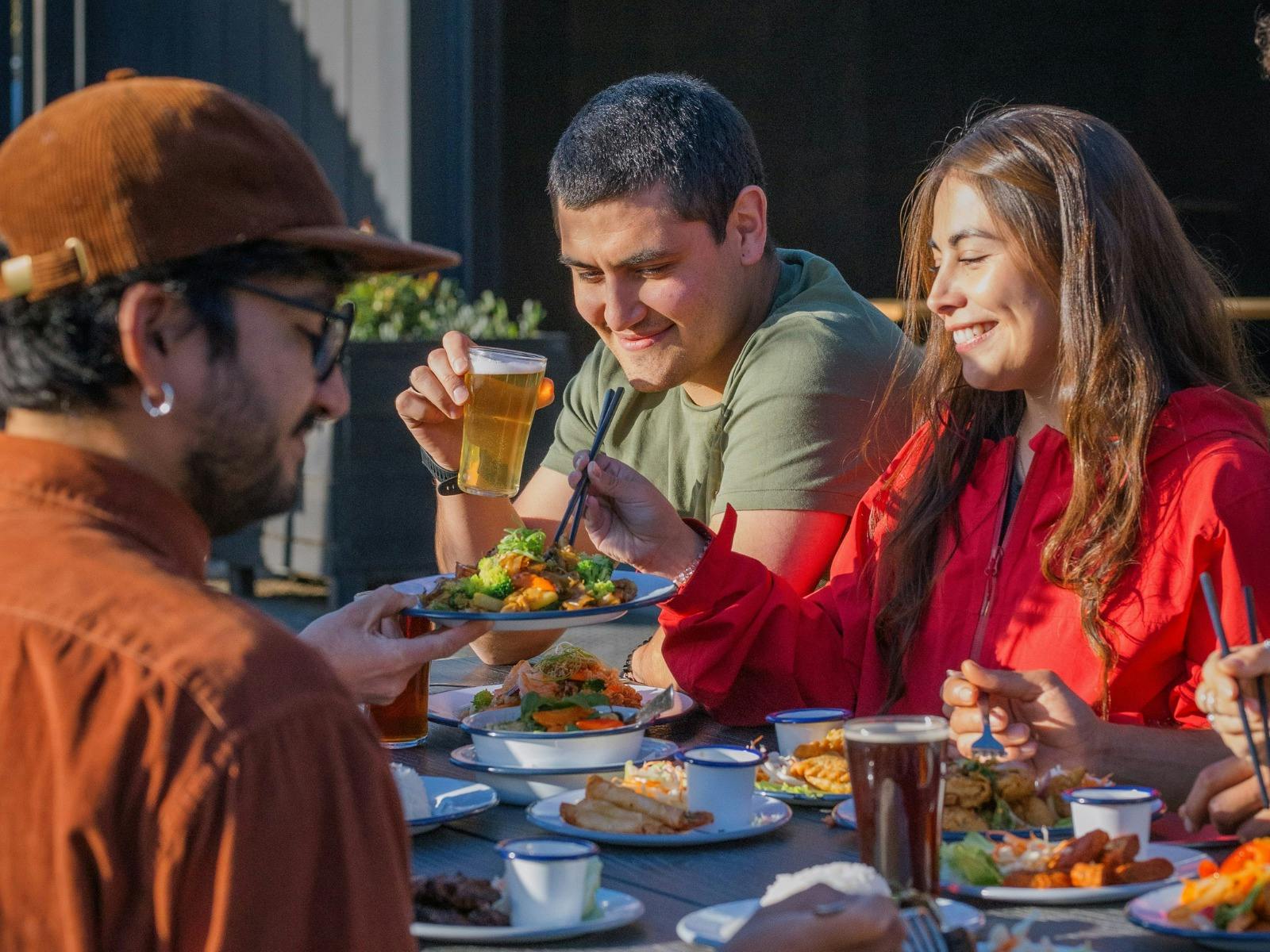 Friends sharing Thai food and drinks outdoors at Easy Tiger in St Helens.