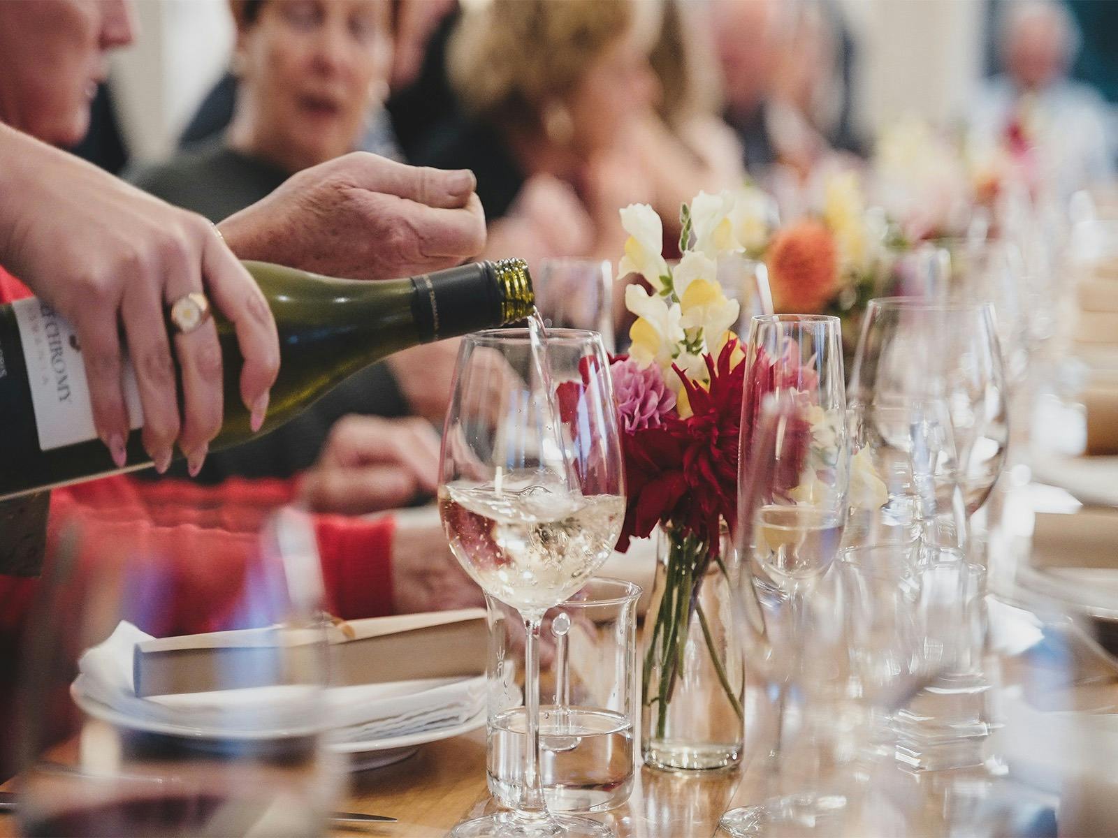 Long table featuring wine glasses and wine being poured