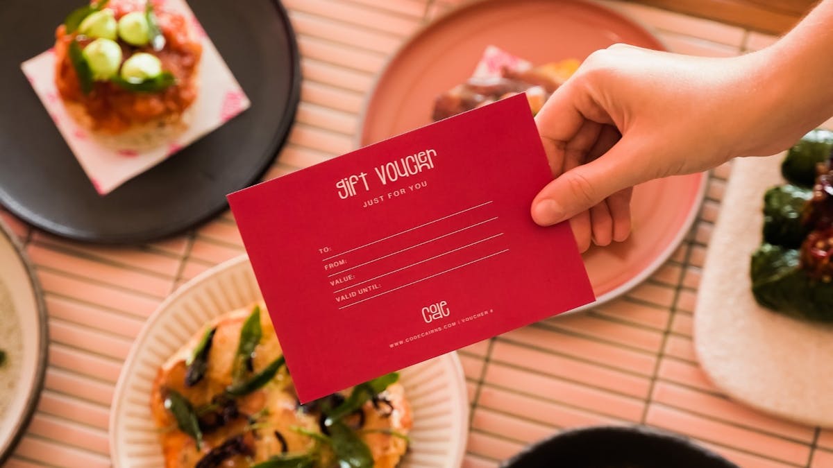 A restaurant voucher is prominently displayed in front of an array of share plates on a table.