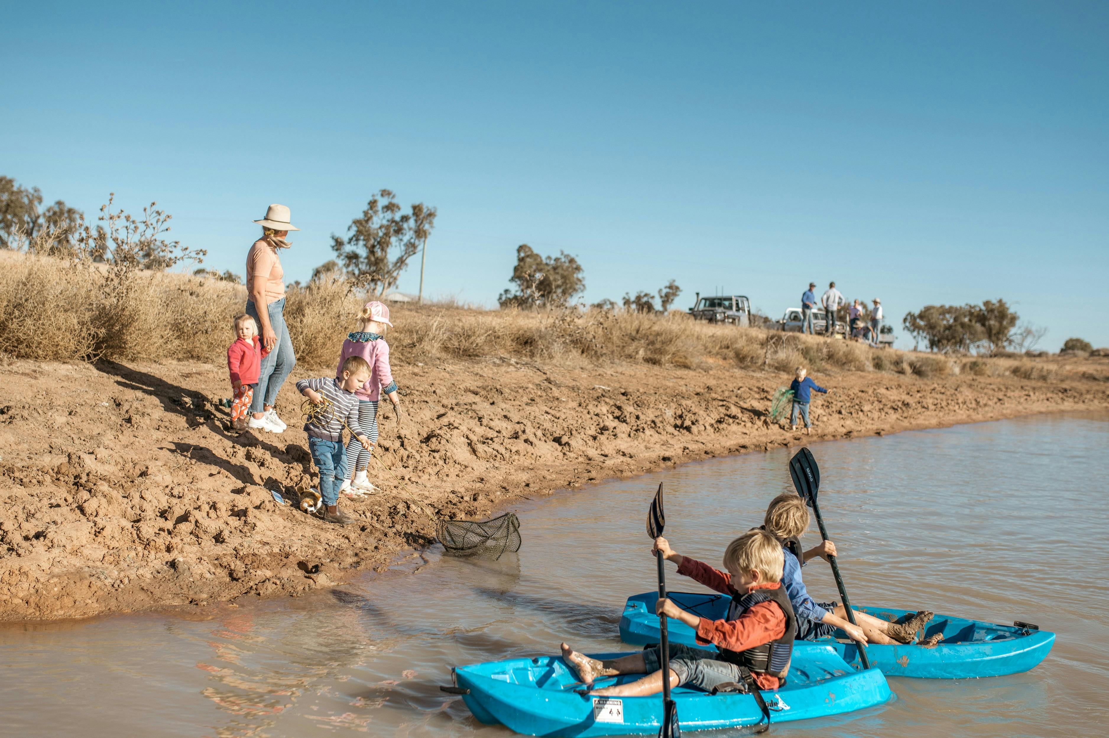 Children kayaking in a dam or lake in the paddock at Gilgooma farm stay camp ground