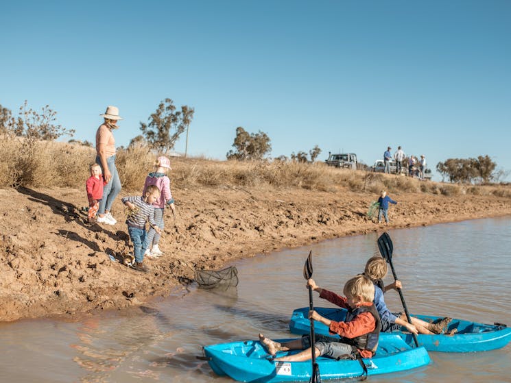 Children kayaking in a dam or lake in the paddock at Gilgooma farm stay camp ground