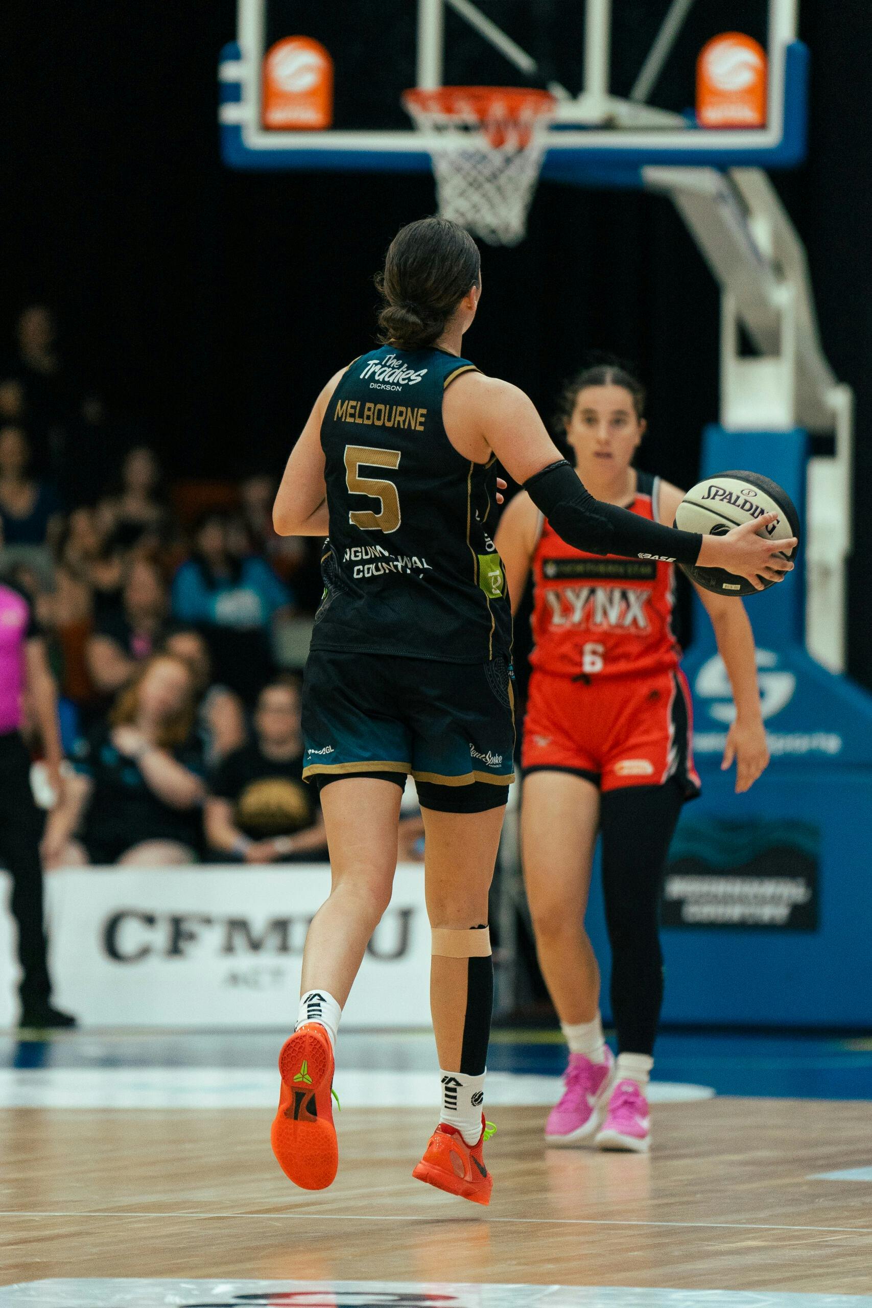 UC Capitals player dribbles the ball up to a Perth Lynx player, squaring up the opposition..........