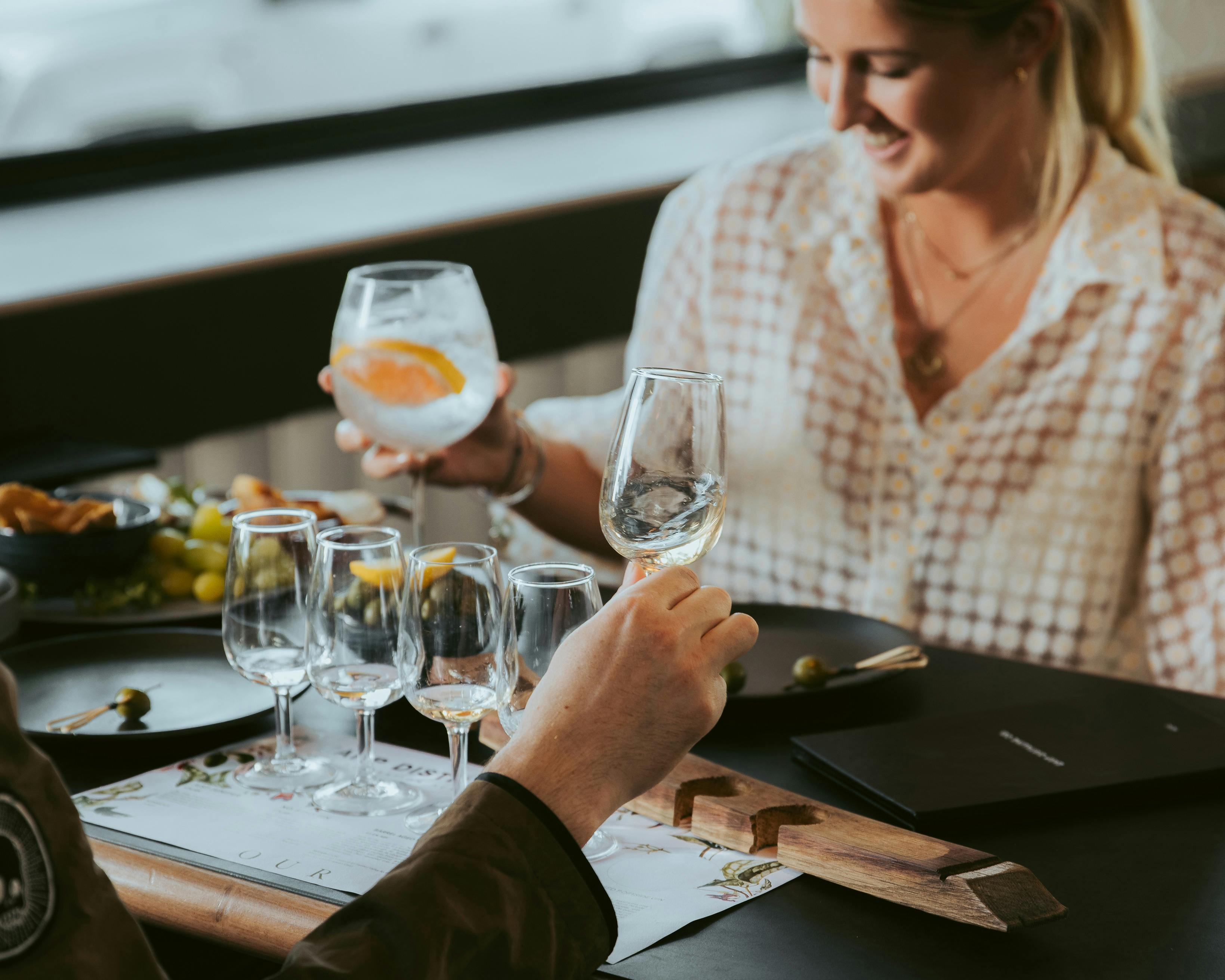 한 커플이 시음용 작은 잔 다섯 잔을 들고 테이블에 앉아 있습니다.