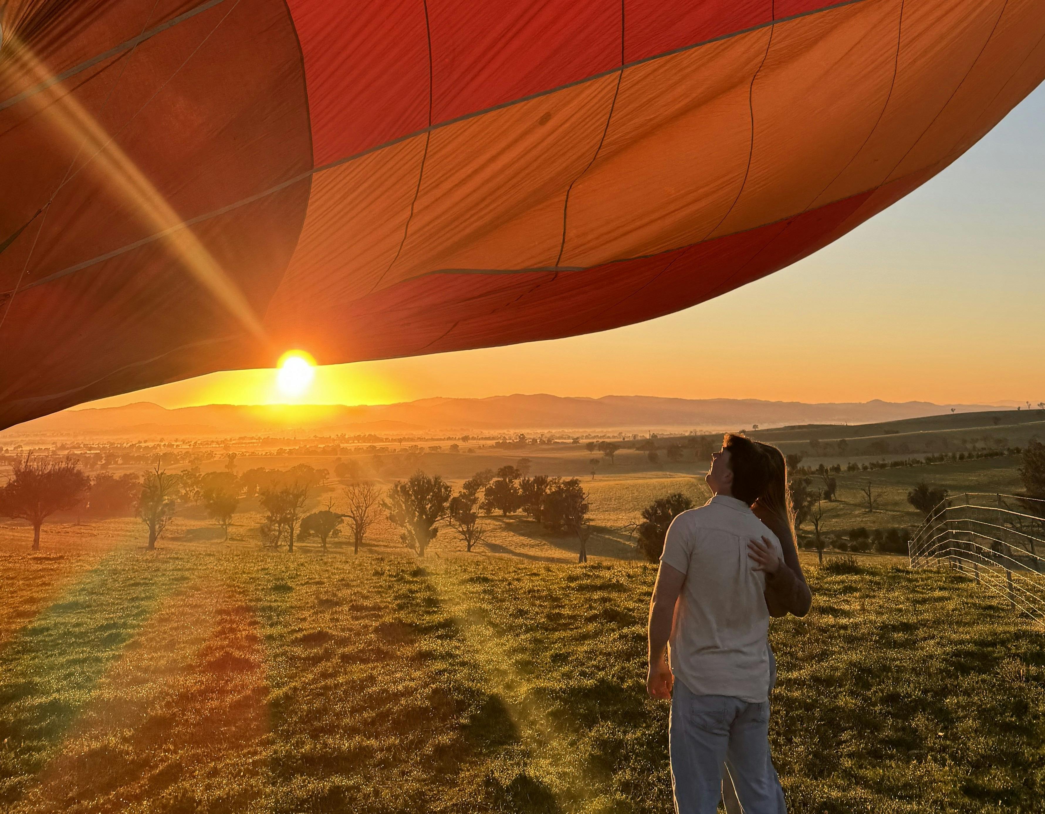Heißluftballon bei Sonnenaufgang mit Paar