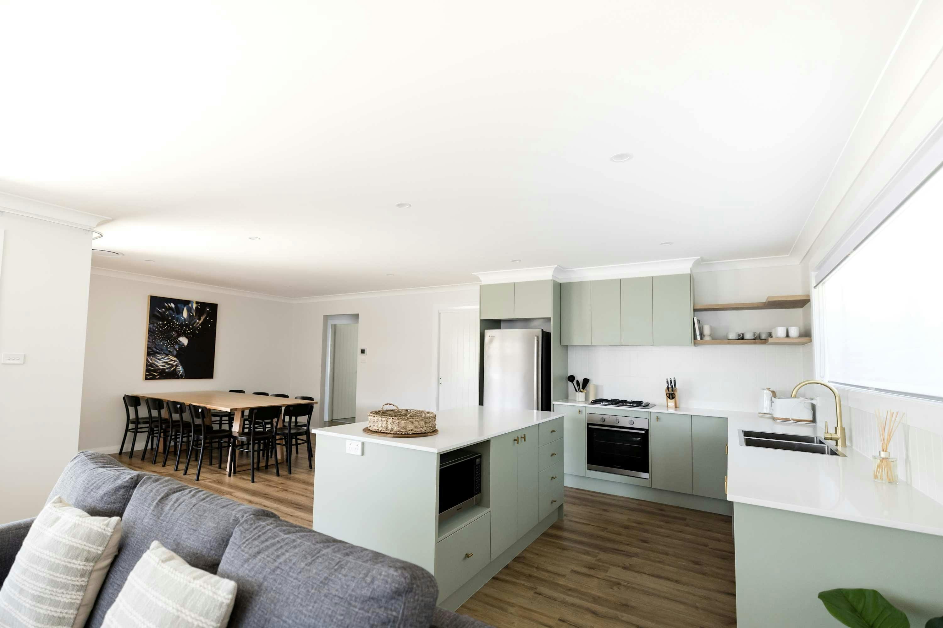 Can see the modern design, layout and style, green kitchen and large 10 seated dining table.