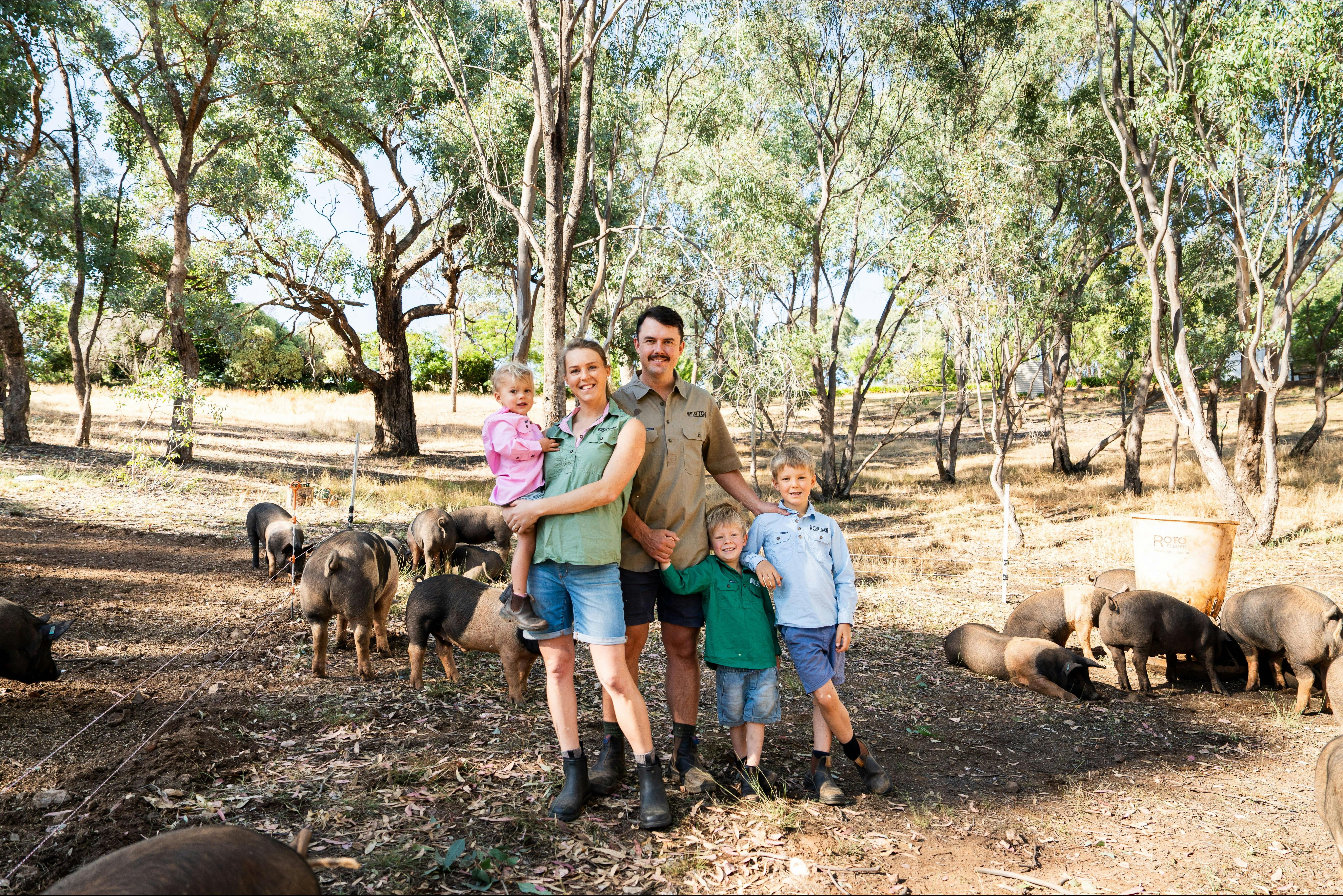 Family outside in paddock with pasture raised pigs