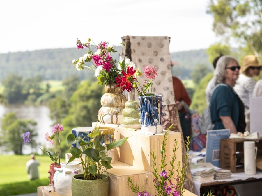 A seleciton of ceramic goods are placed on a table outdoor with river views behind
