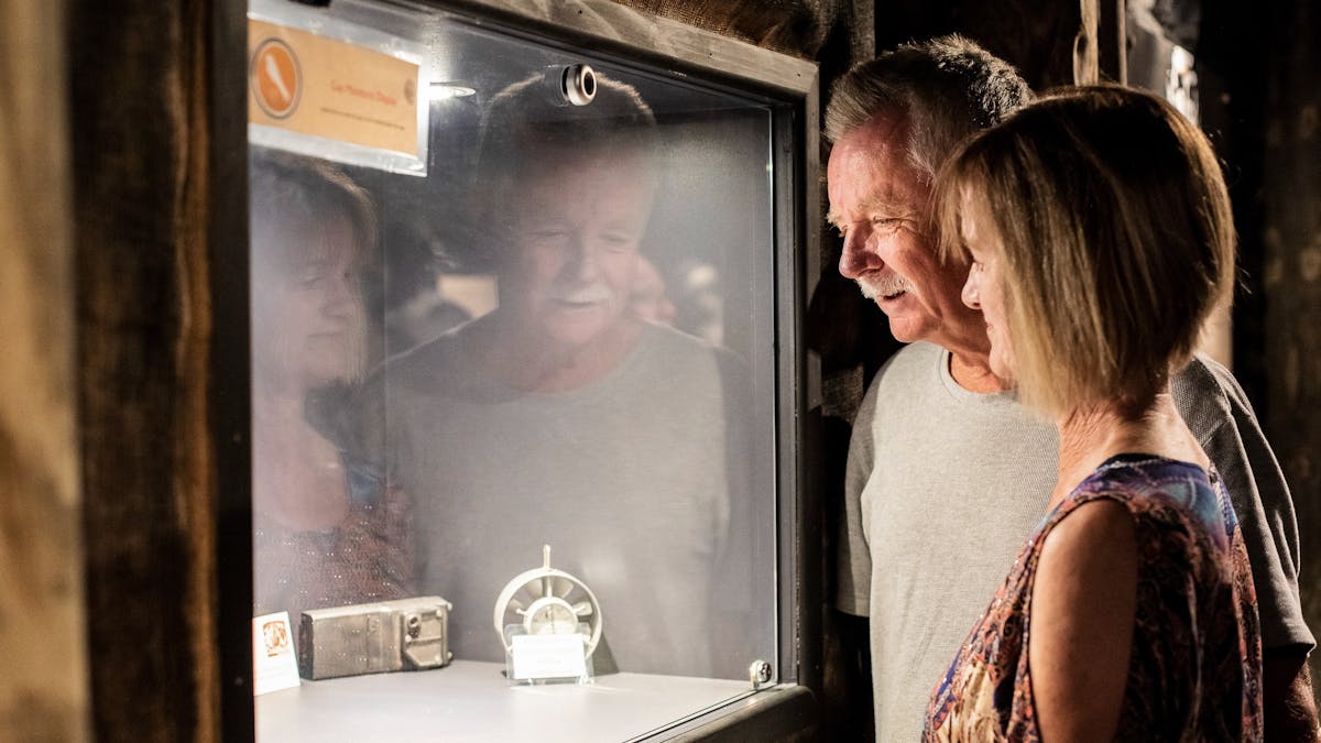 Lady and man looking into glass display cabinet  with small exhibits inside the museum