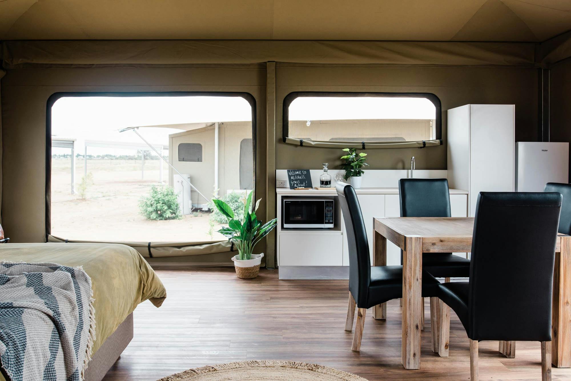 Dining table in Mulga tent and white cabinets in kitchenette