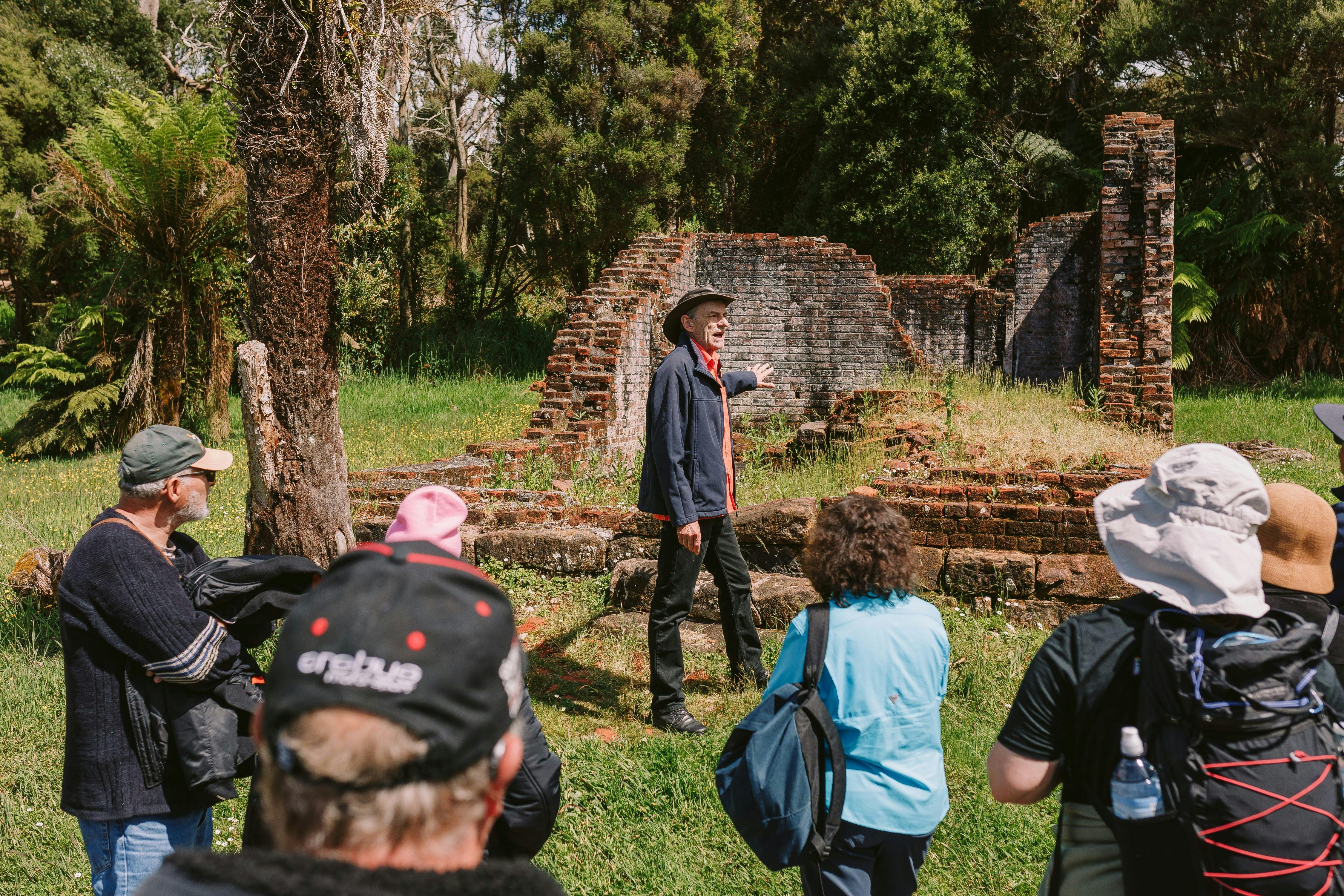 Tour guide speaking to a small group of people standing in front of convict ruins.