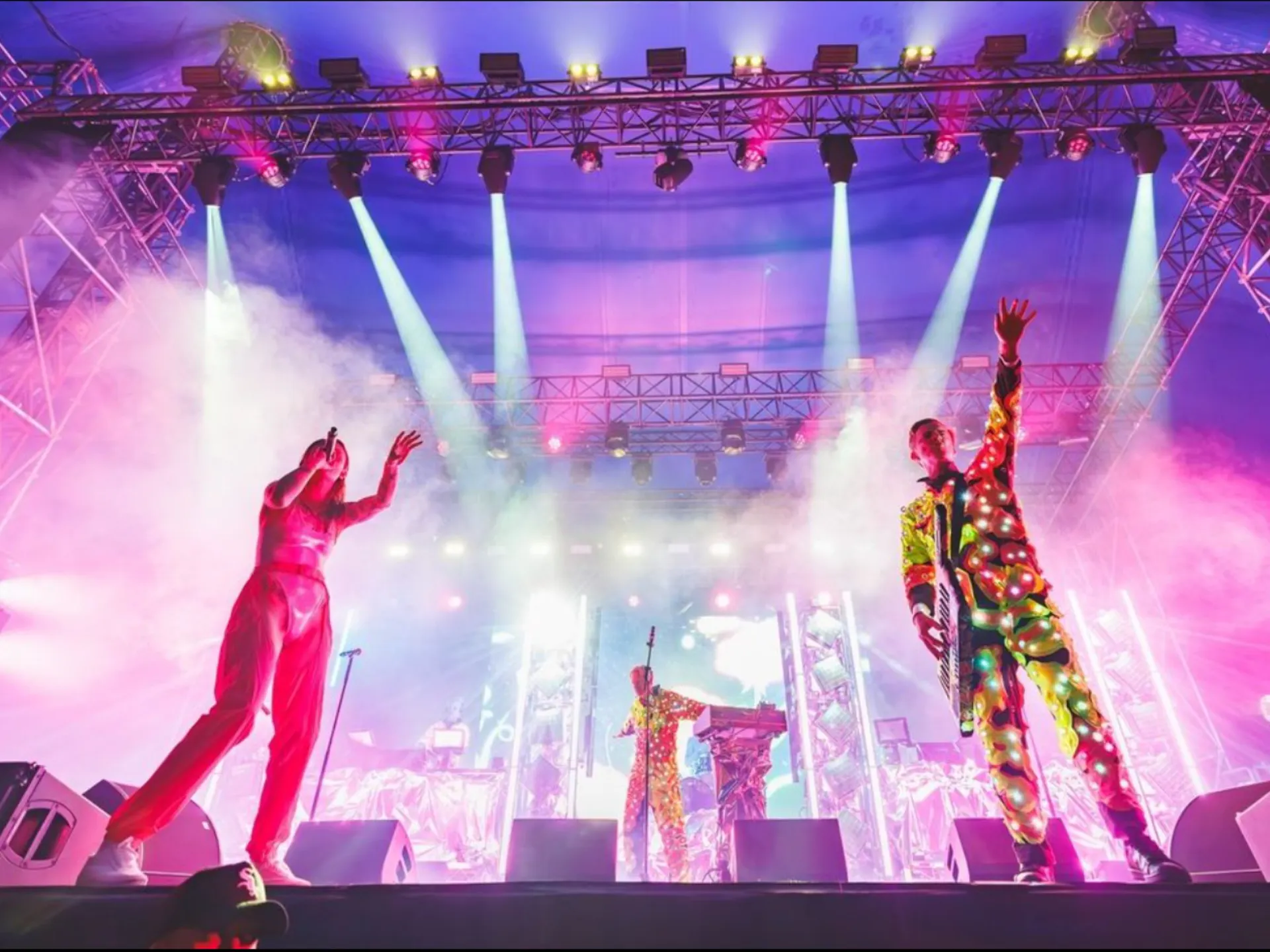 Live shot of PNAU. Bright blue and pink lights illuminate the performers and stage.