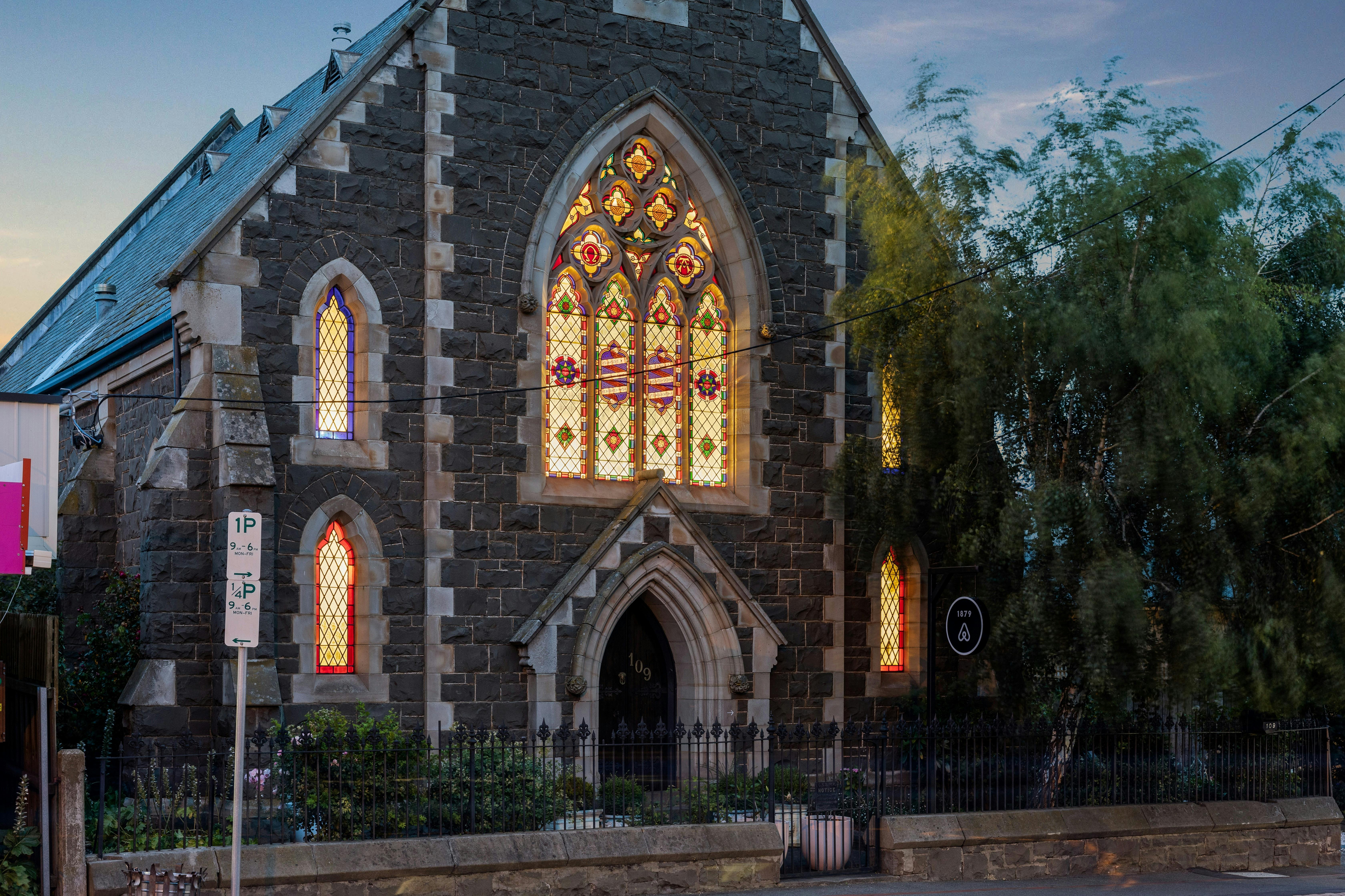 historic bluestone church at dusk, with stained glass windows lit from within