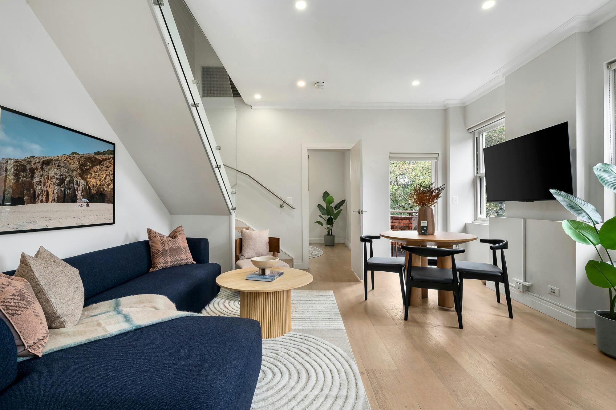 Spacious open plan living area with dining set, couch, coffee table and wall mounted TV.