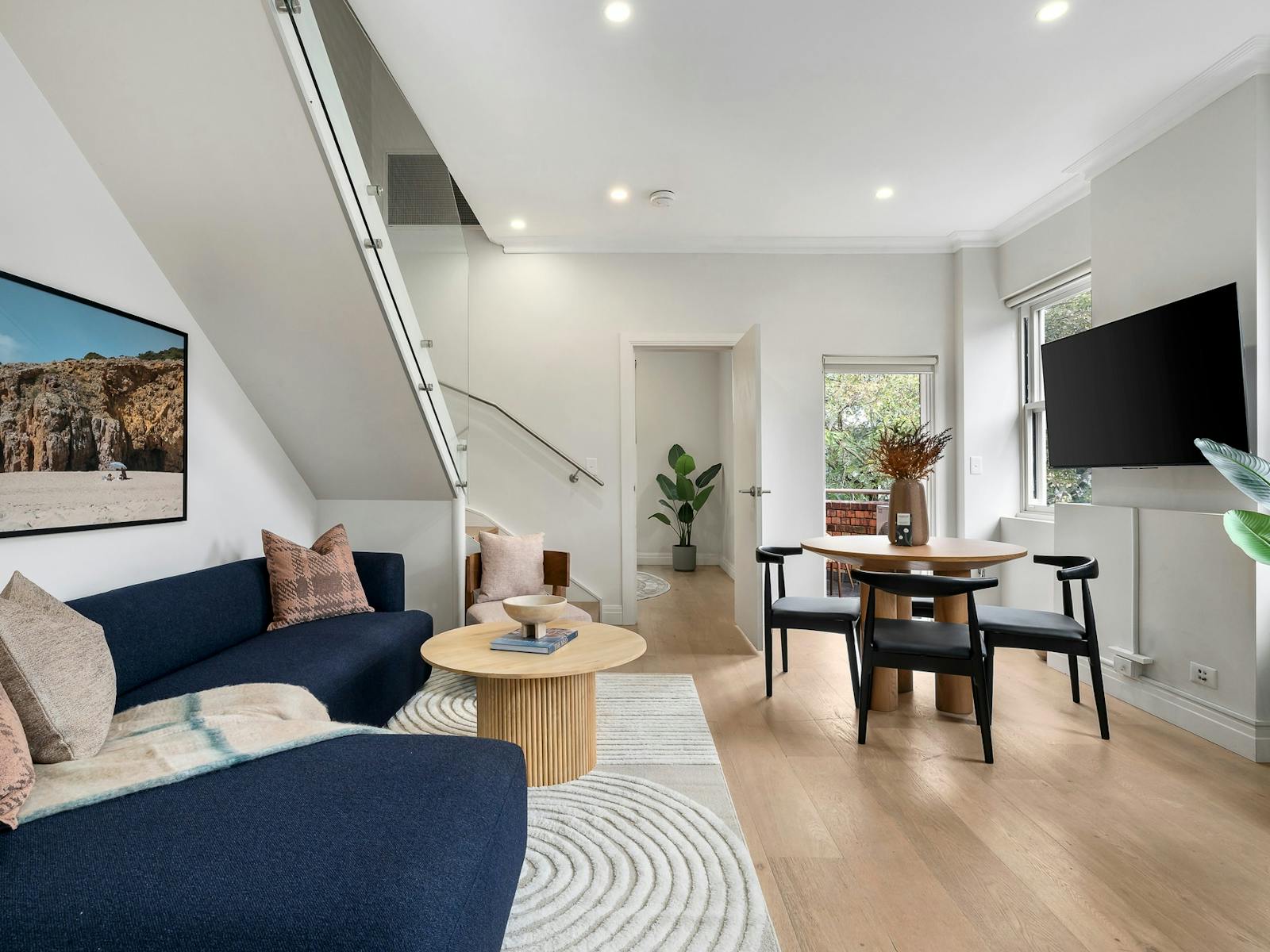 Spacious open plan living area with dining set, couch, coffee table and wall mounted TV.