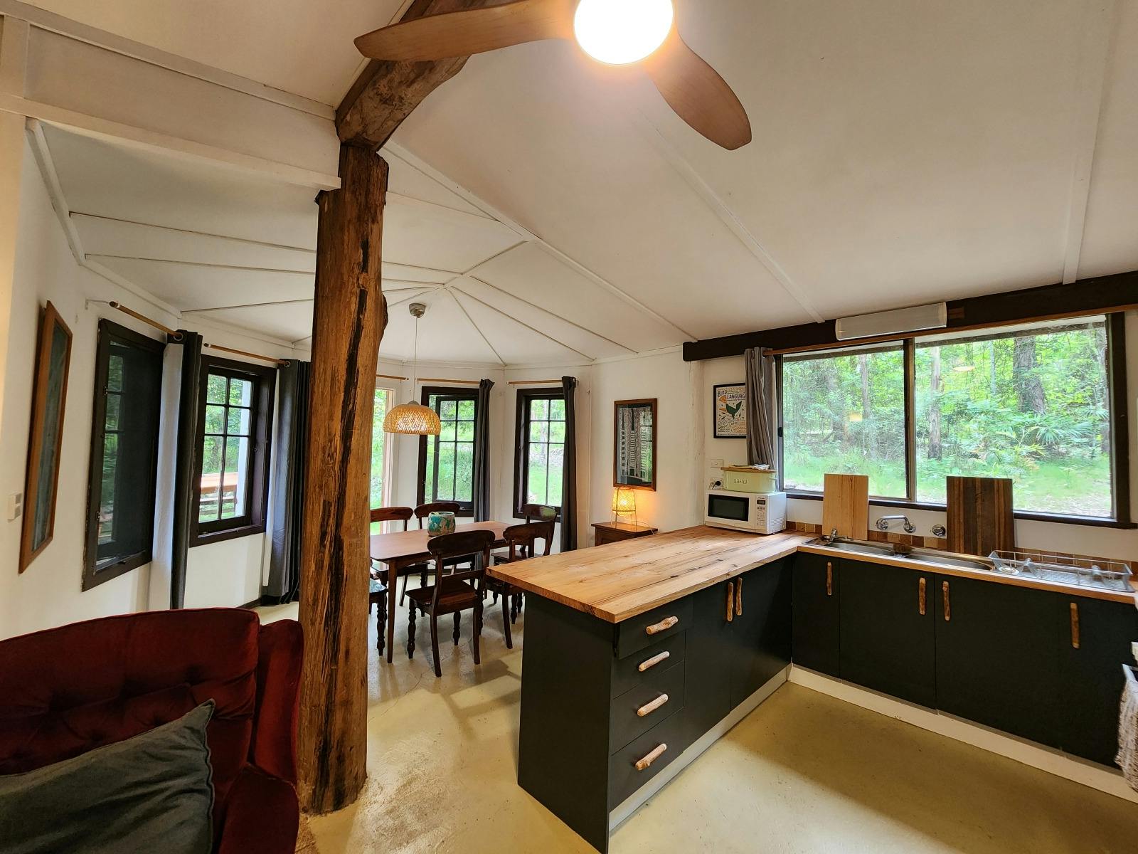 Clancy Cottage's open plan kitchen, lounge, dining room looking out to forest at Wangat Lodge