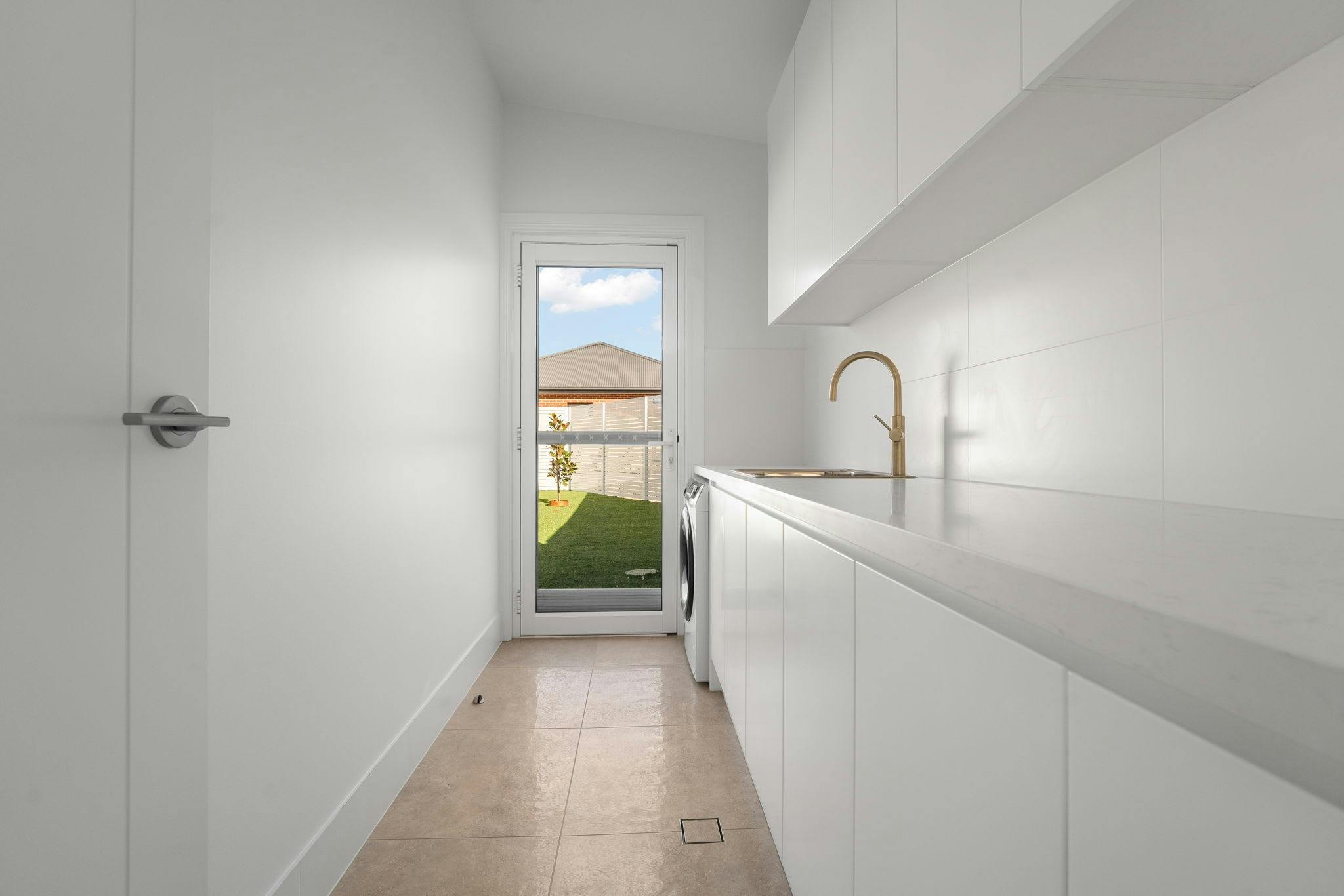 Large white walls, cabinets, bench tops with a door leading to the backyard