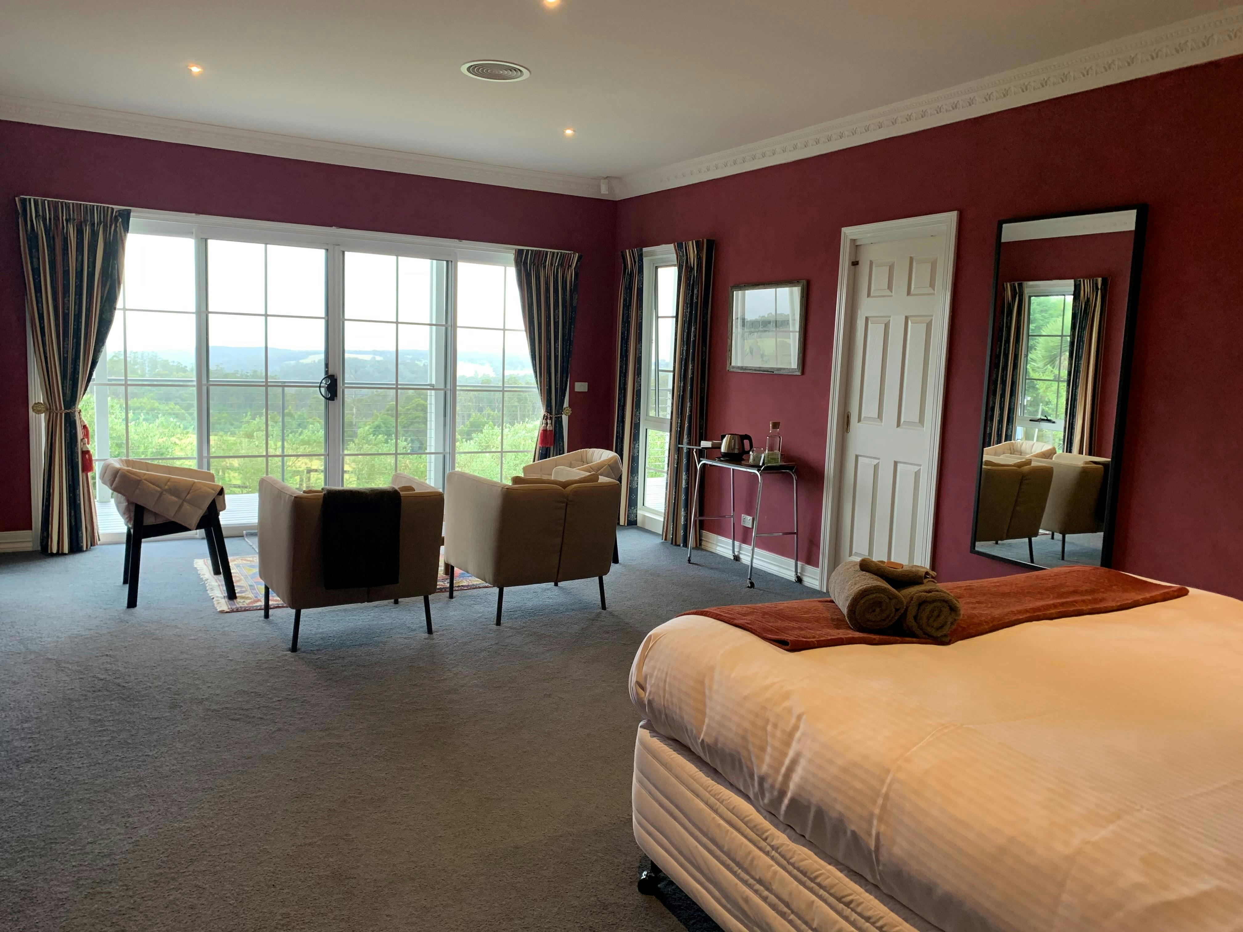 A large room with a king size bed, a lounge area and an ensuite bathroom