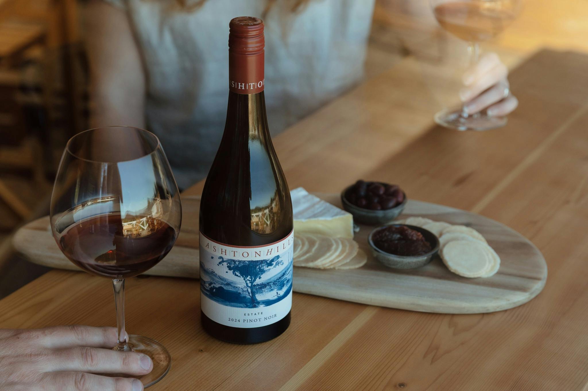 A Glass and Bottle of Ashton Hills Pinot Noir with a cheese board