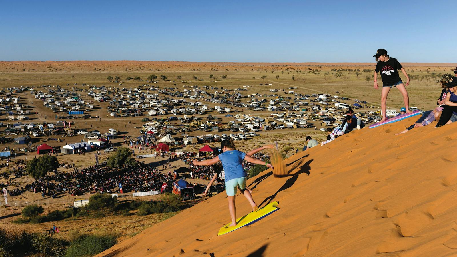Sandboarding down the side of Big Red in Birdsville at the Big Red Bash