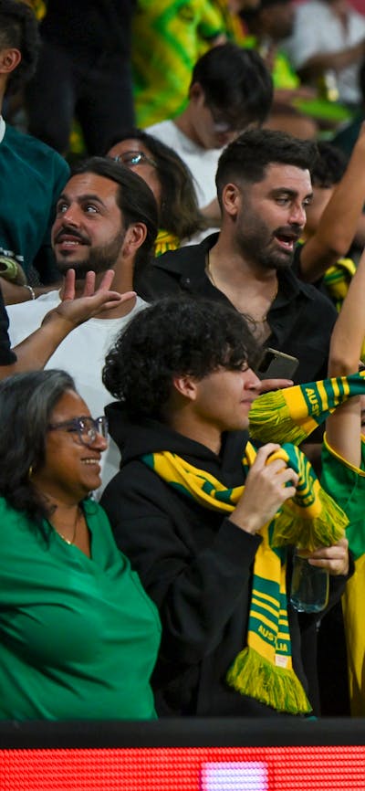 Soccer players in yellow kits celebrate a goal on a stadium pitch as teammates run in behind