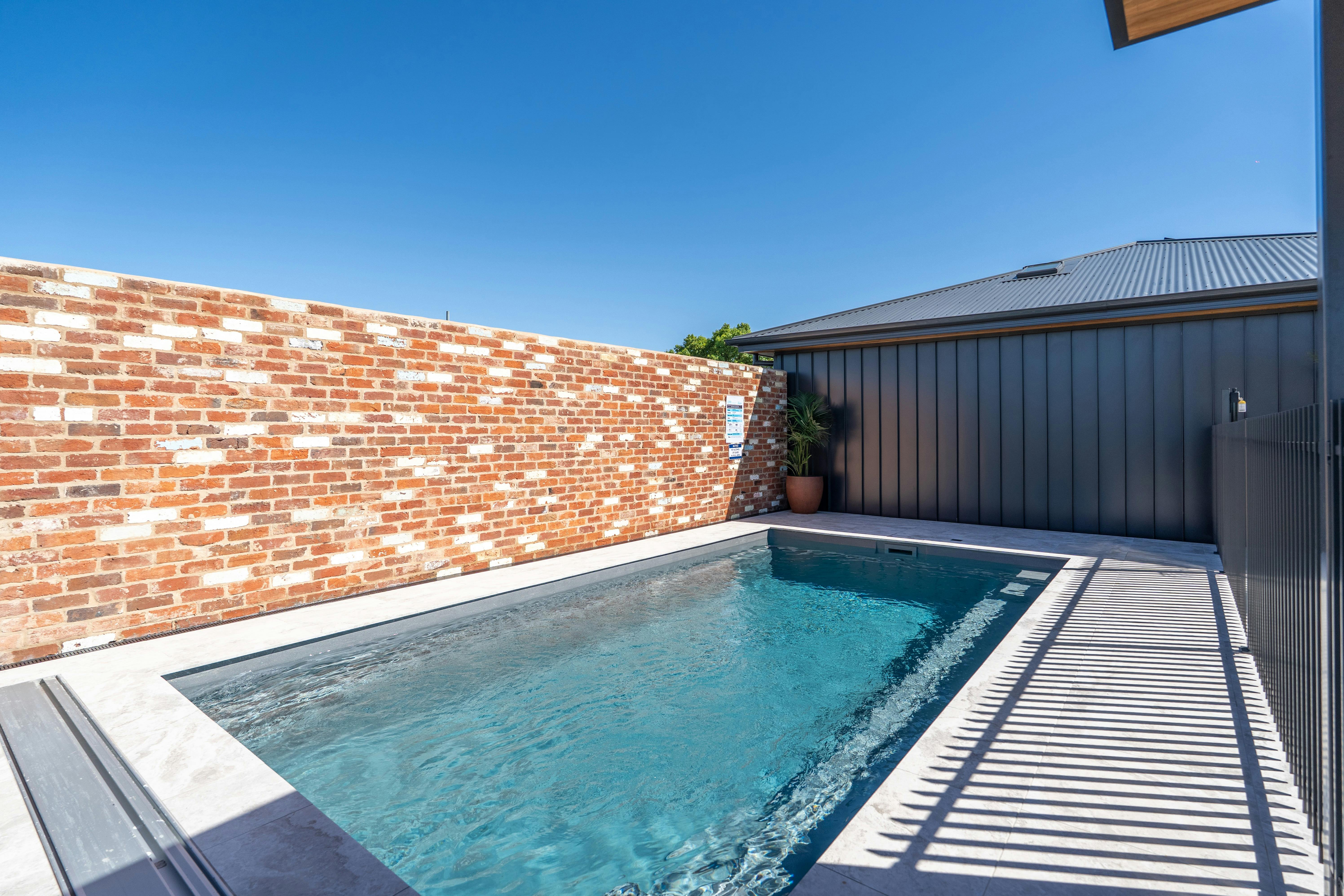 Communal pool and bbq area for all the guests at Ropa Suite. There is a fence and a brick wall.