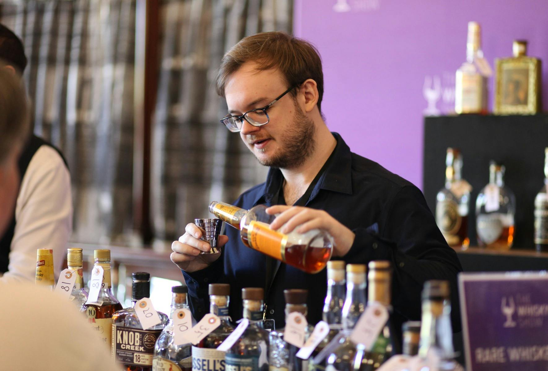 A man pours a vintage American Whiskey with a deep amber colour