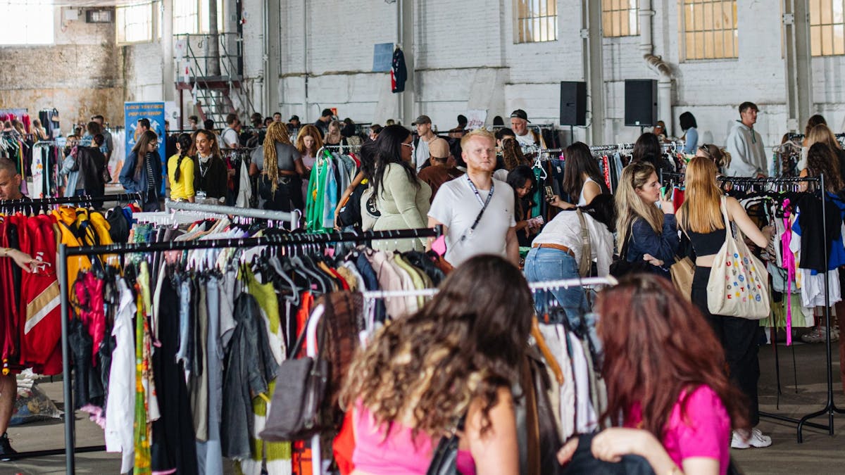 pictured is a view of the market with lots of racks of clothes and people