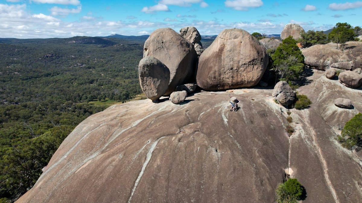 Two people sitting on a huge granite outcrop with massive granite boulders behind them