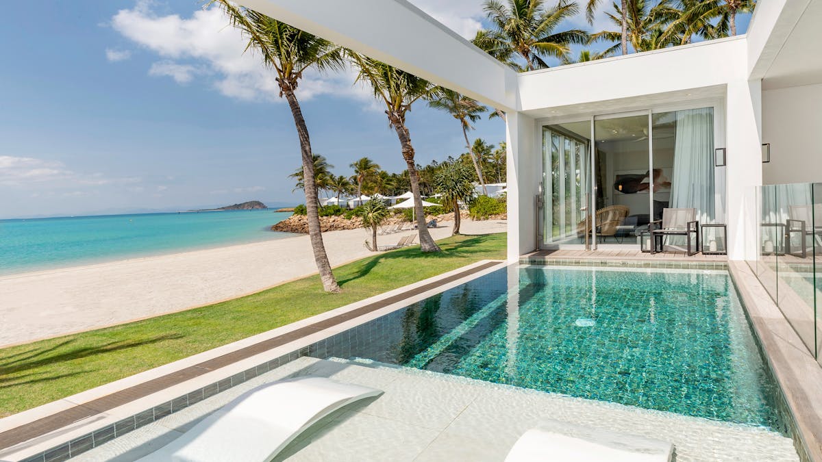 Private pool overlooking a white sandy beach, turquoise water, and palm trees.