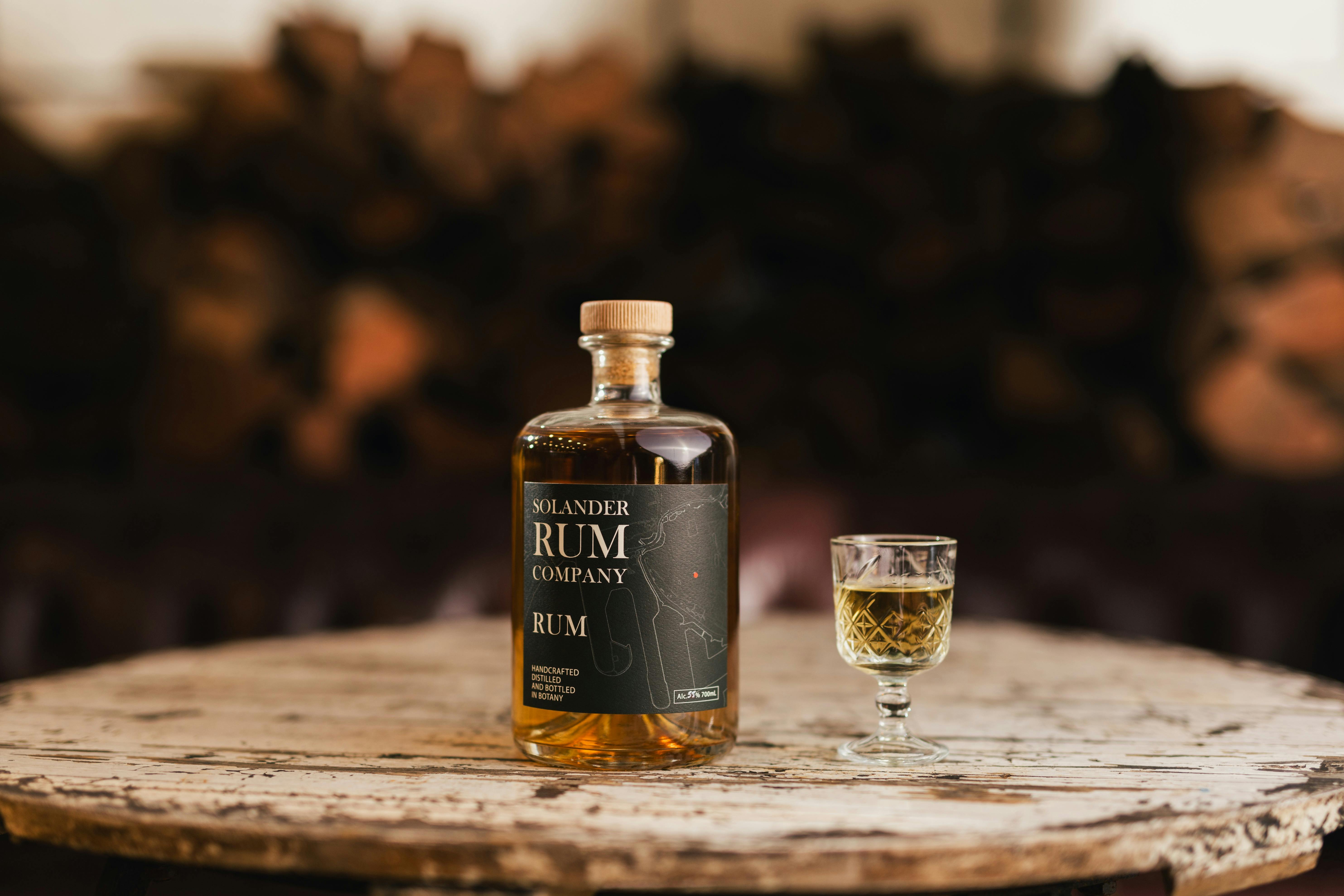 Bottle of Rum on a round table with chopped wood behind it