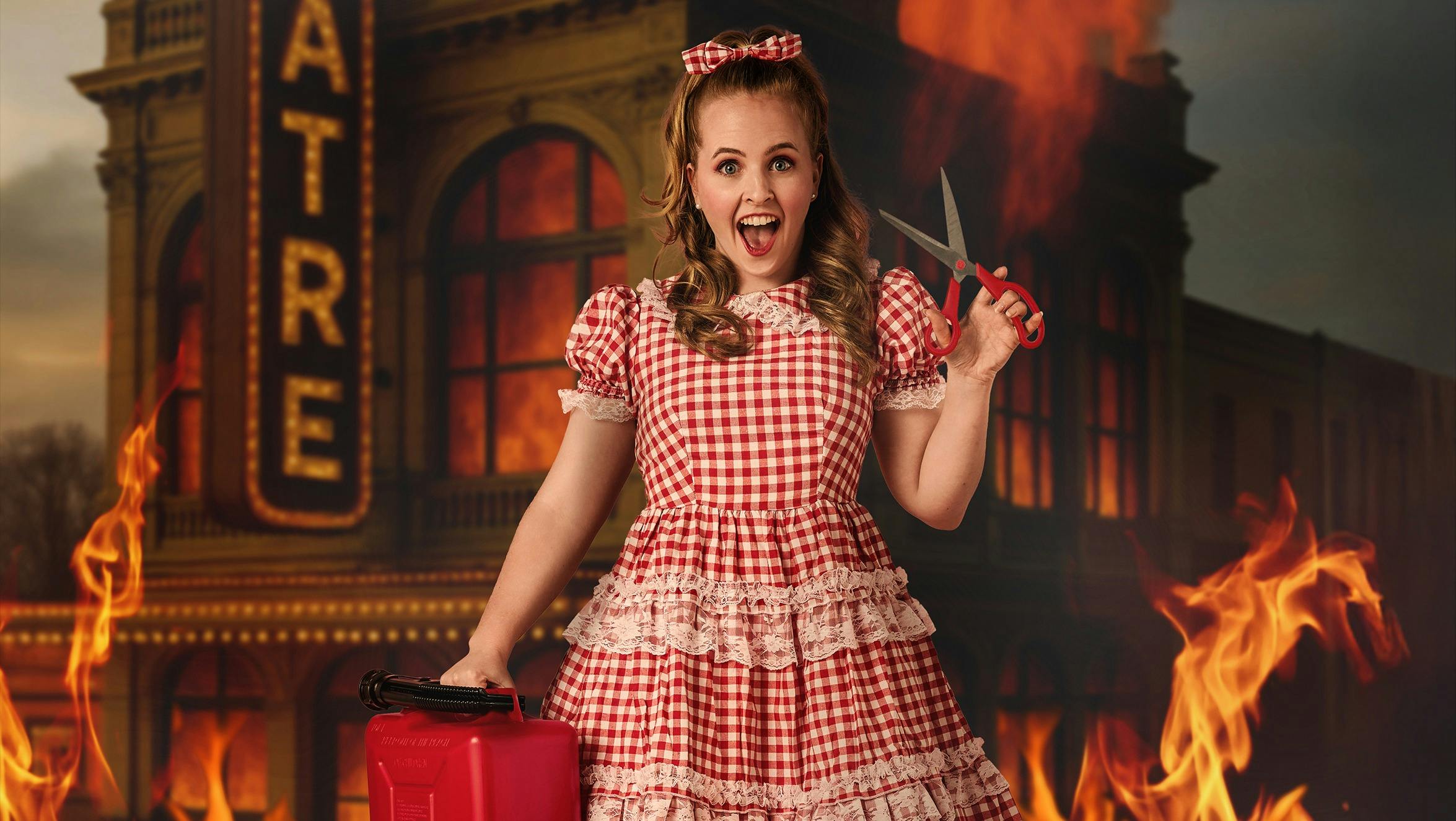 A performer in a red gingham dress holding scissors and petrol can, in front of burning theatre
