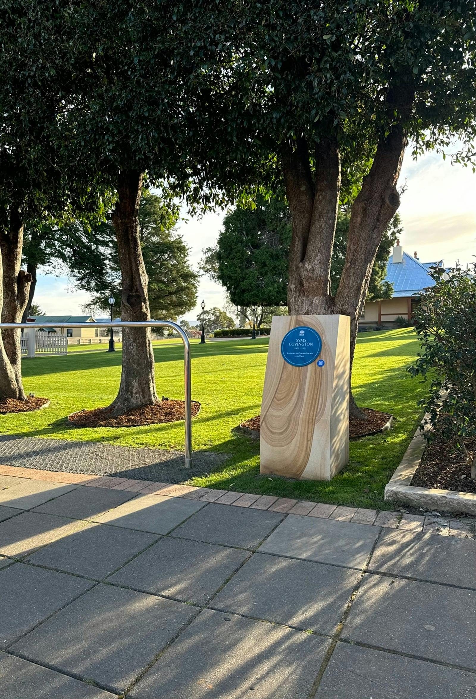 Blue plaque on sandstone plinth in park setting