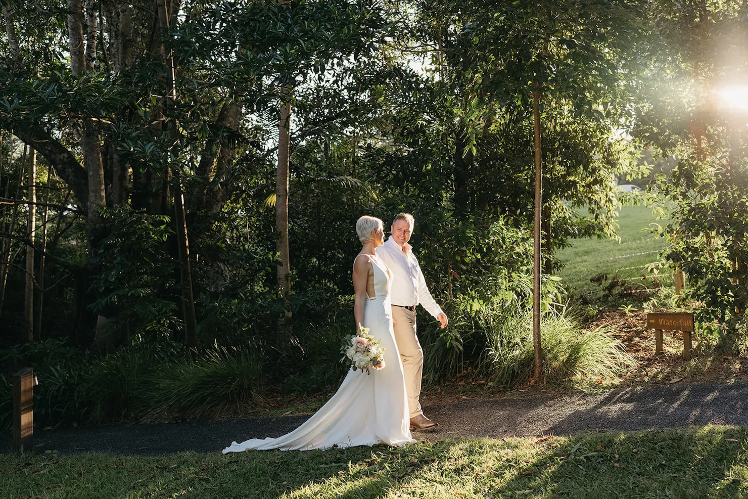 A couple in wedding attire walking across the retreat lawns