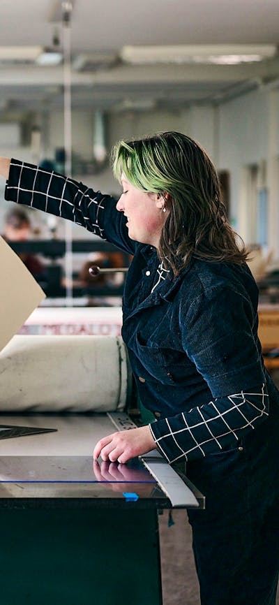 A person pulls a large print on an etching press