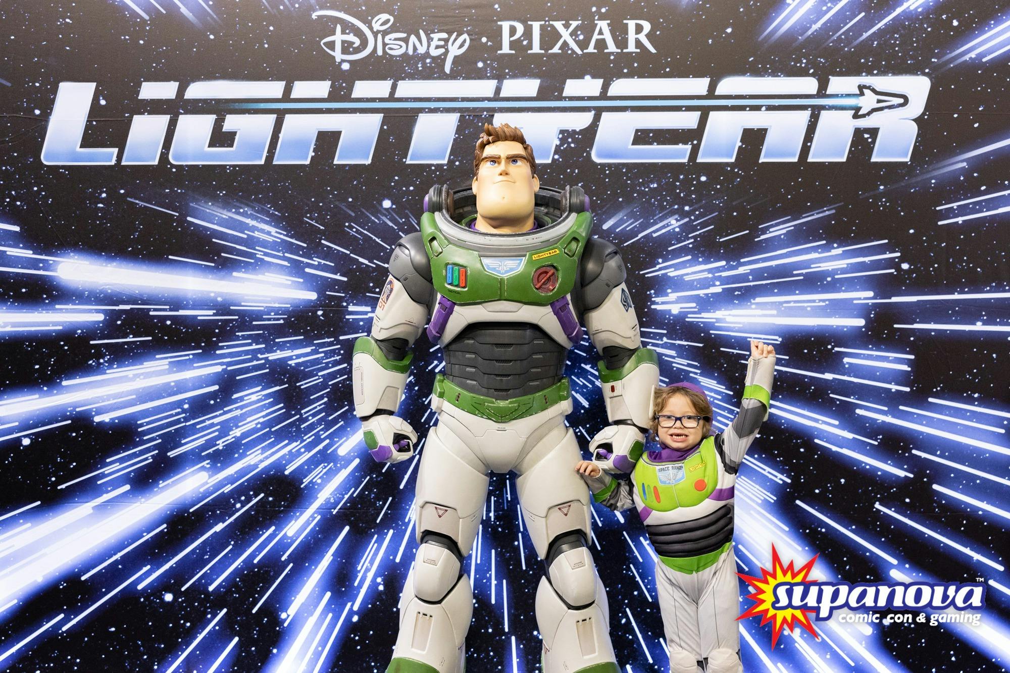 Little legend dressed up as Buzz Lightyear poses next to Buzz Figurine