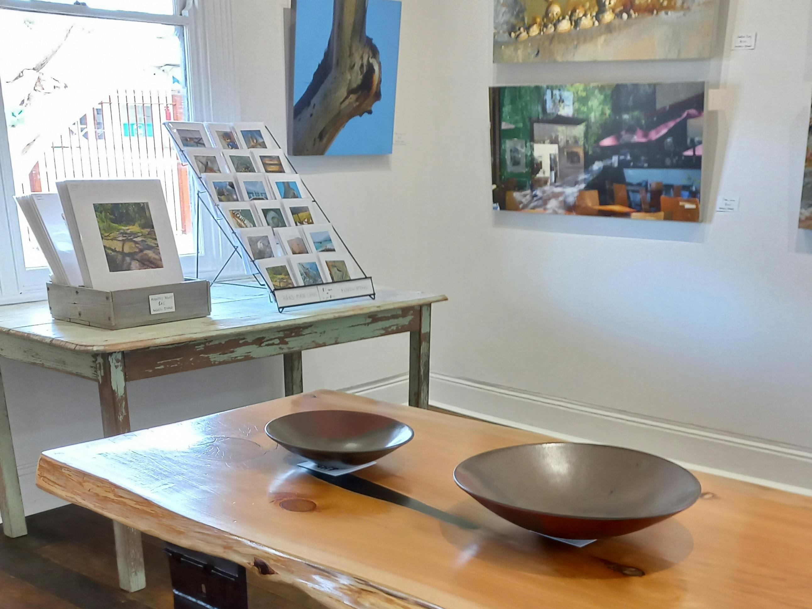 A view inside the ART Gallery, depicting Photograhy, cards, prints, pottery and Cypress slab table.