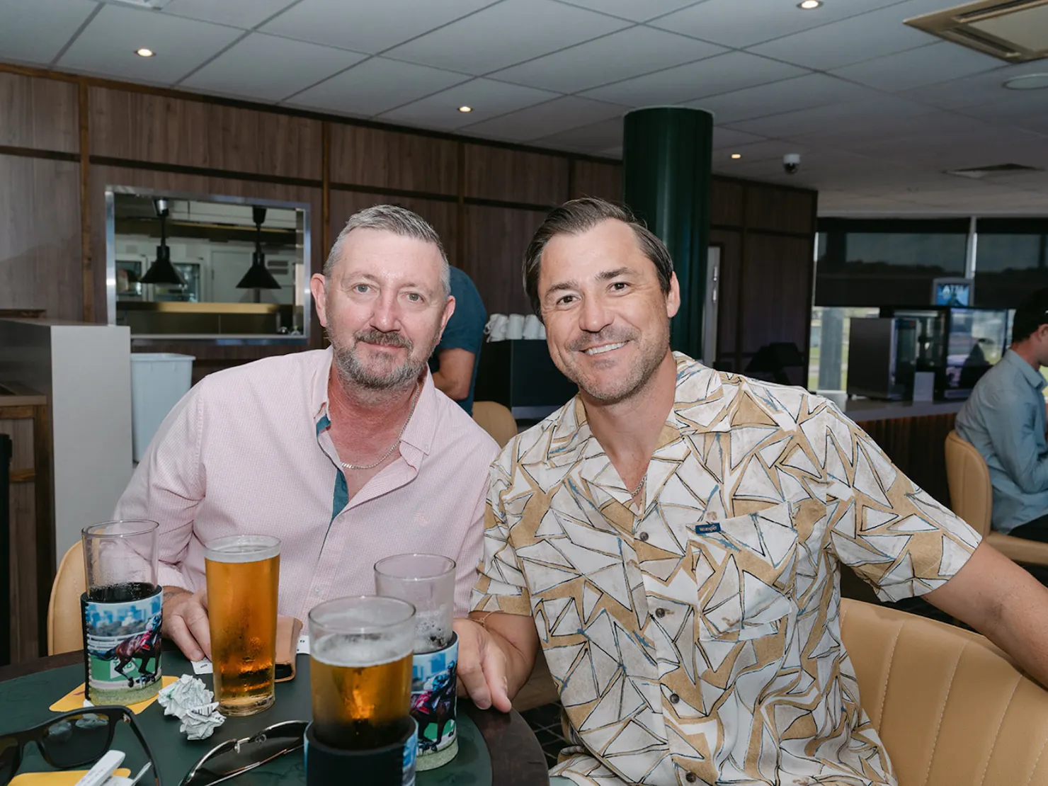 Two men smiling at the camera with drinks