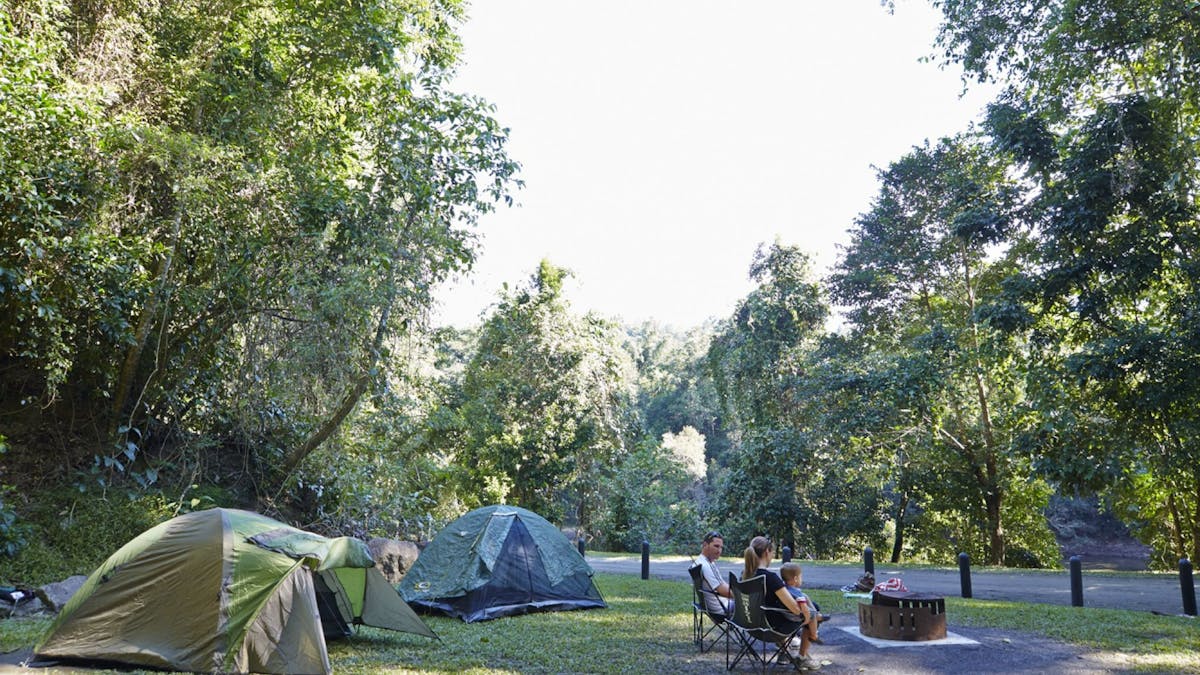 Family sitting around fir ring with tents set up in the background.