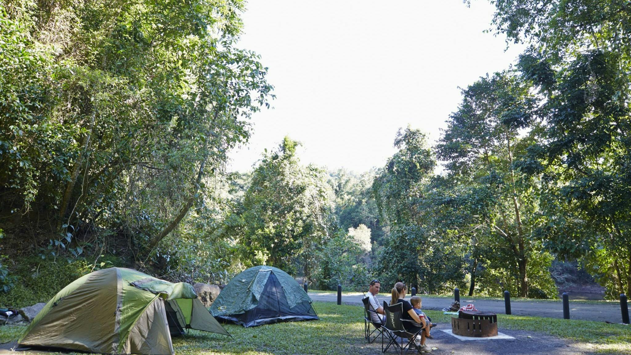 Family sitting around fir ring with tents set up in the background. Family sitting around fir ring with tents set up in the background.